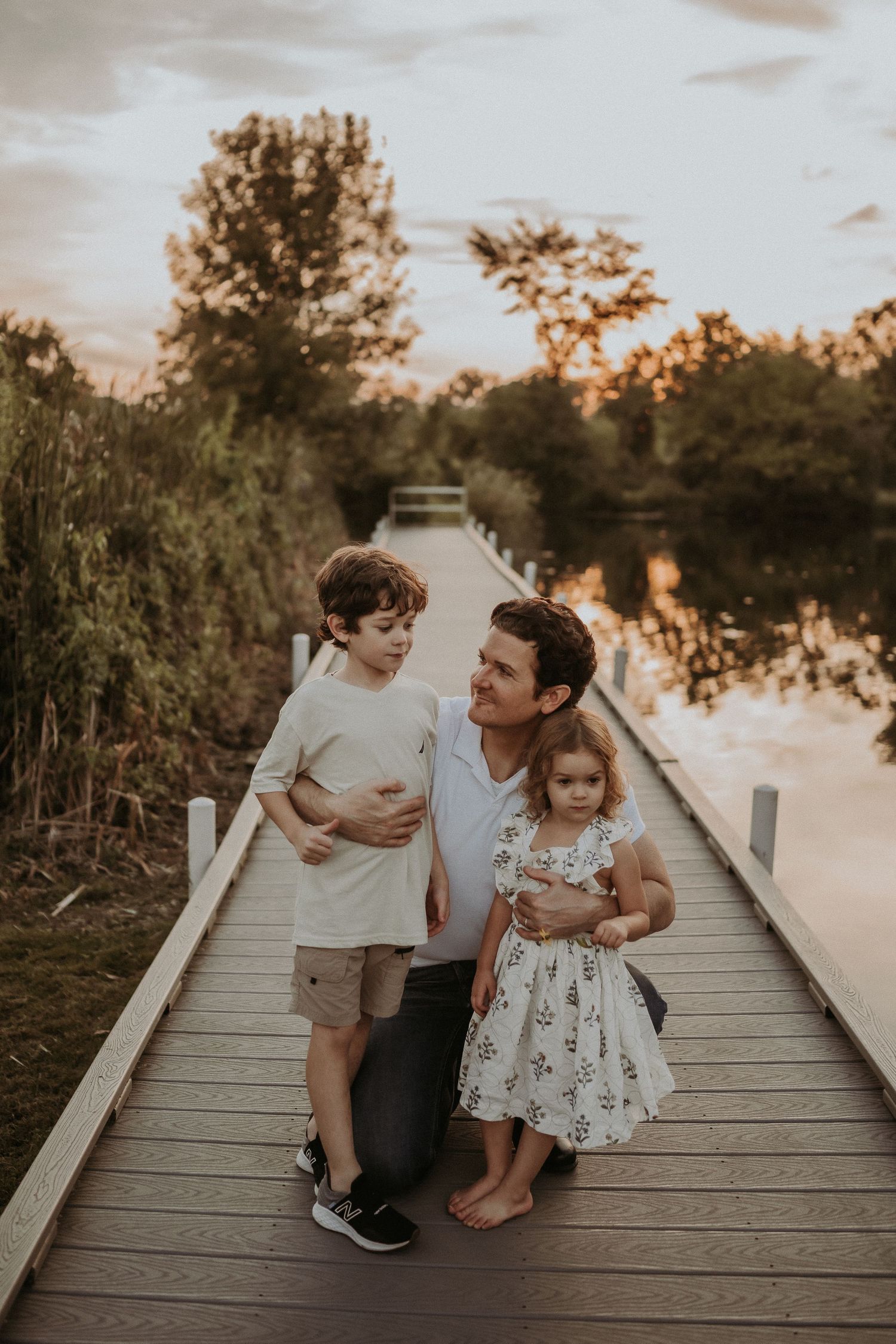 Family enjoying a tender moment together on a waterfront boardwalk at dusk.