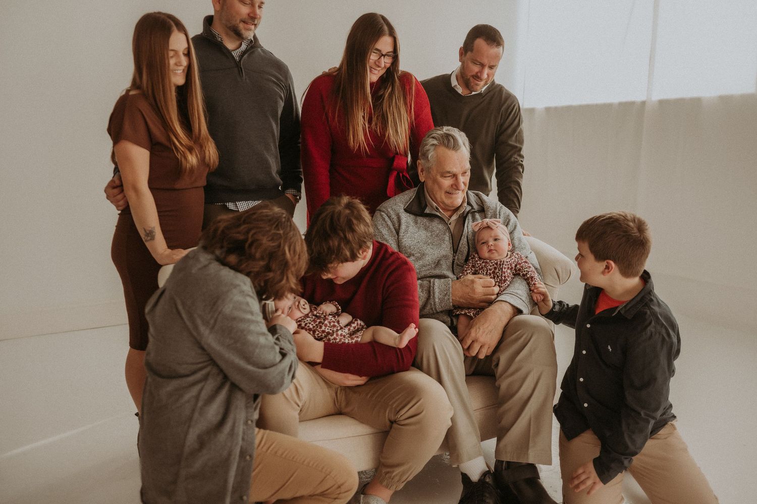 Family gathering for a casual portrait session with babies in matching outfits.