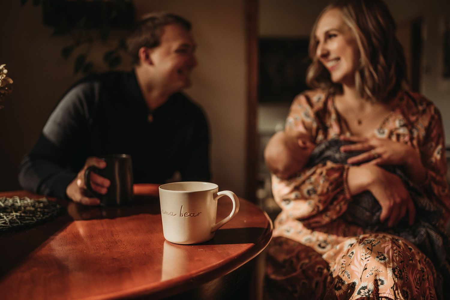 Couple enjoying coffee together at wooden table in warm ambient lighting.