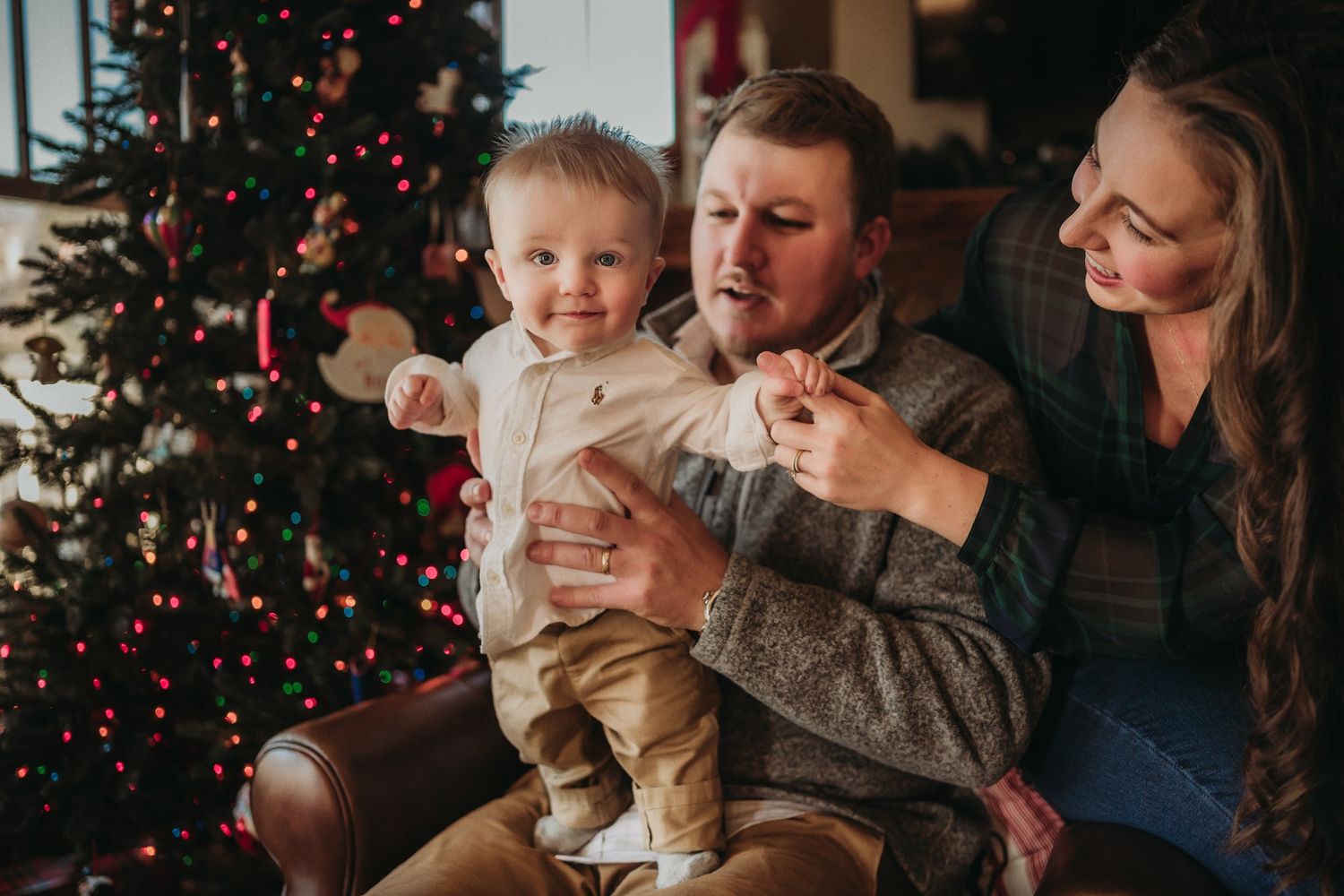 A family enjoys playful moments together in front of their festive Christmas tree.