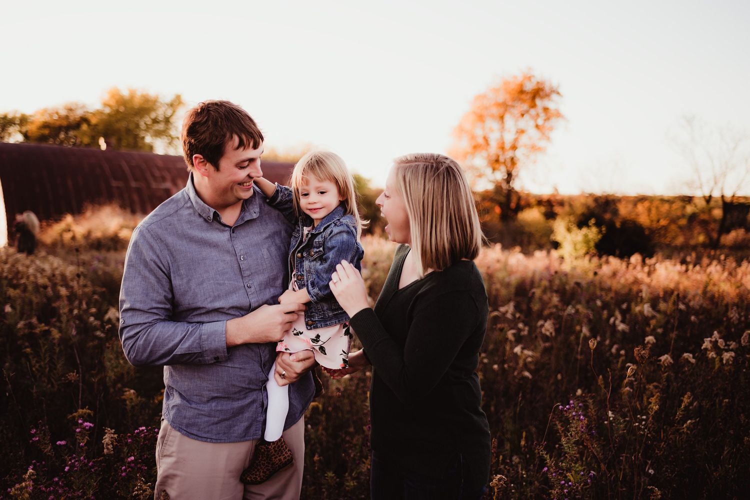 Family sharing joyful moment together during golden hour in autumn field.