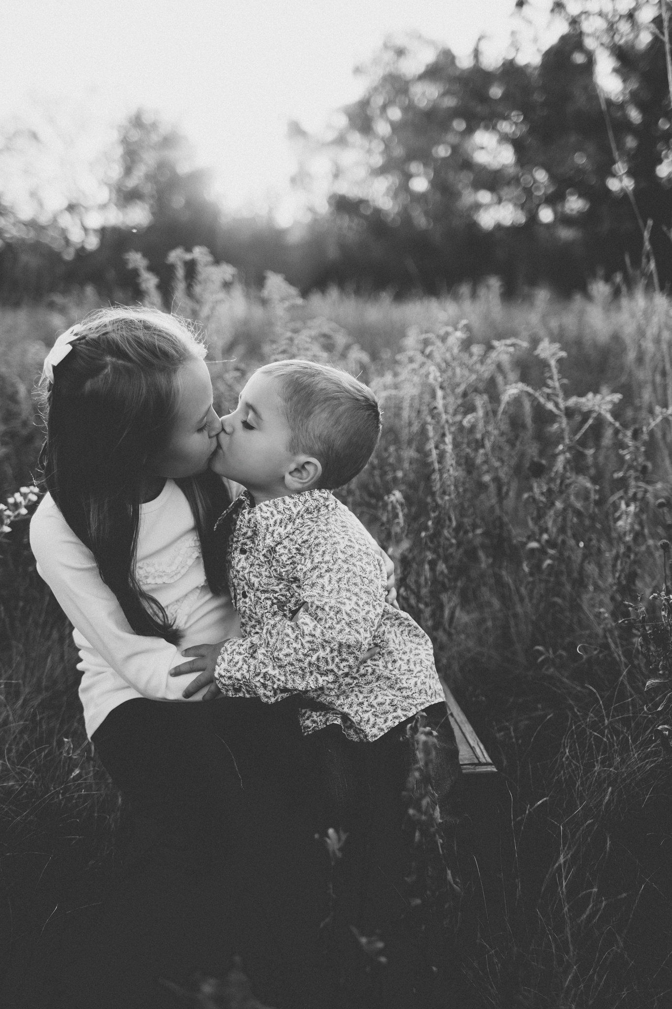 Black and white portrait of parent and child sharing an intimate moment in wild grass.