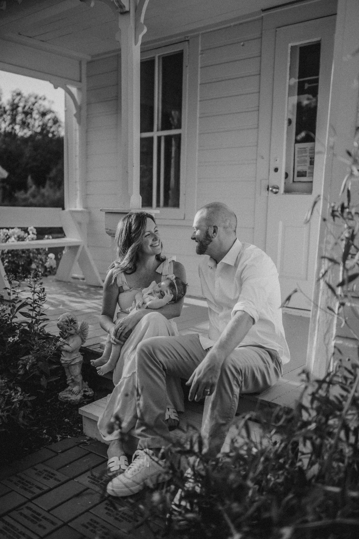 A couple sitting together on a farmhouse porch during a relaxed photo session.