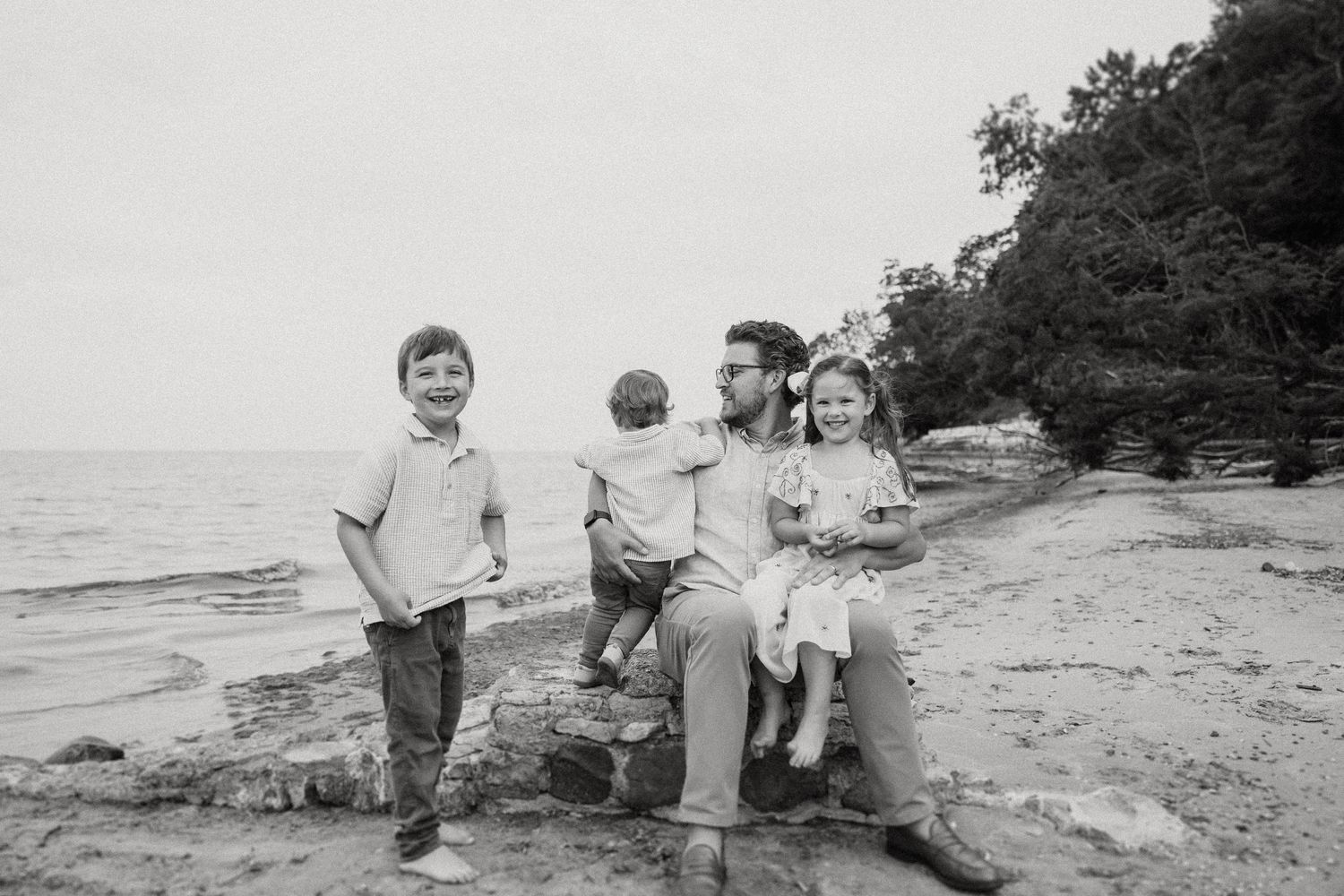 A black and white portrait of a group seated on coastal rocks.