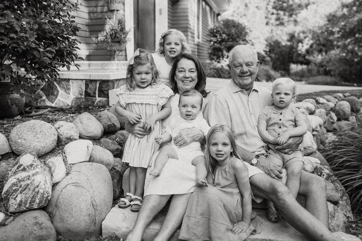 Black and white photo of family members gathered on stone steps in front of a house.