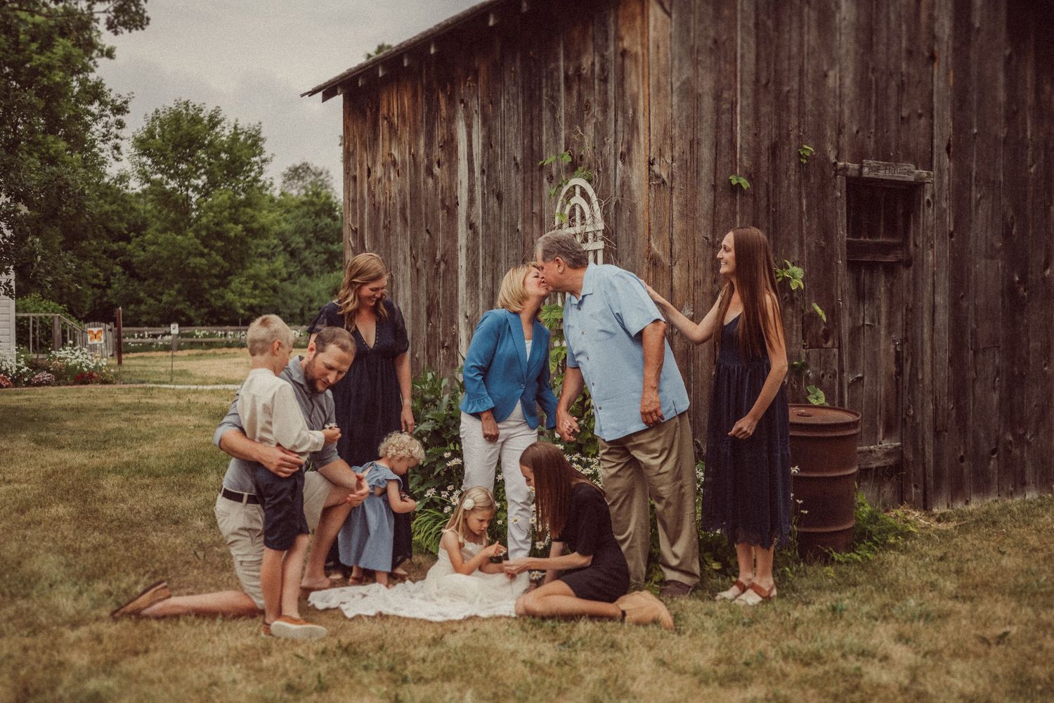Group gathering outdoors in front of rustic wooden barn on a sunny summer day.