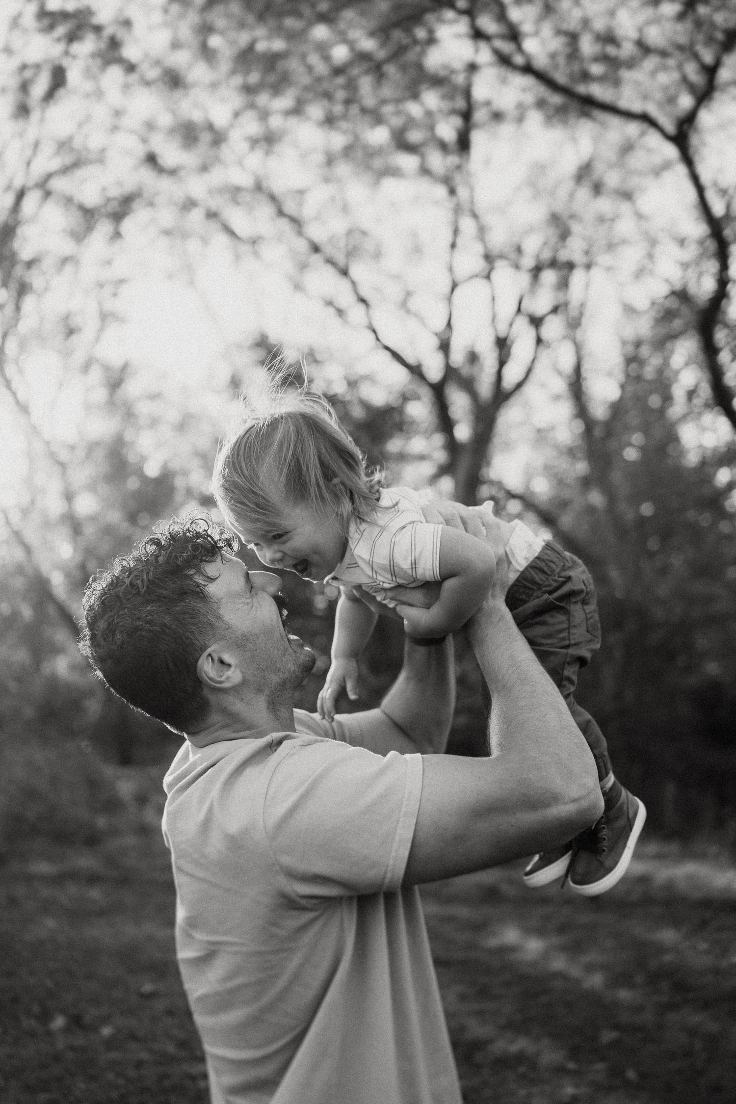 Black and white portrait of a playful moment outdoors during golden hour.