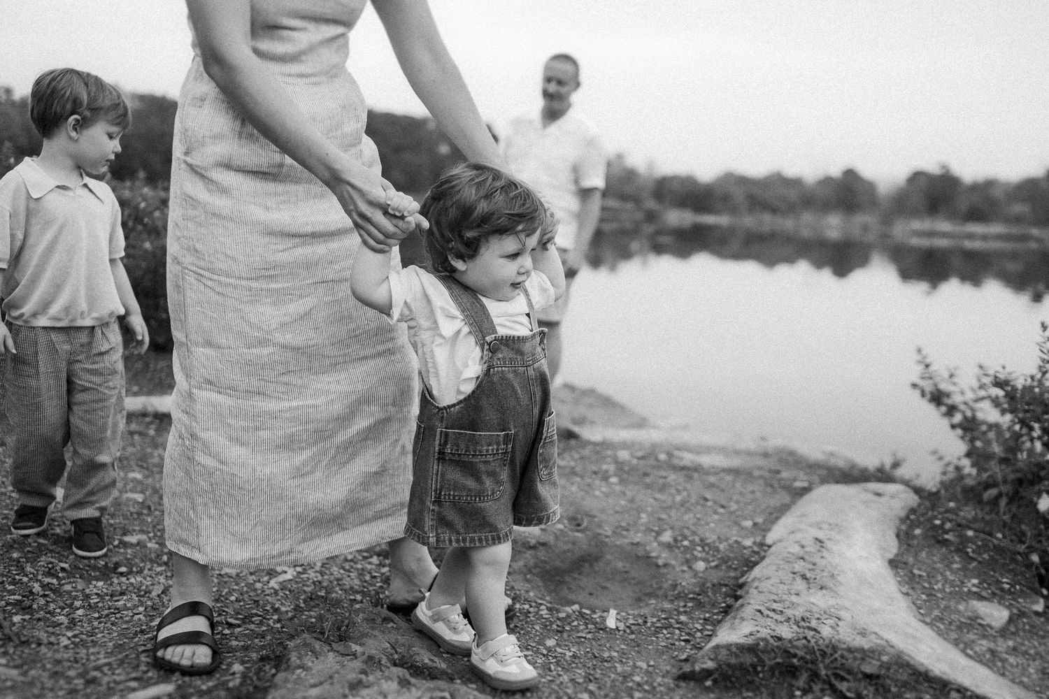 A vintage black and white photograph showing people gathered near a peaceful lake or pond.