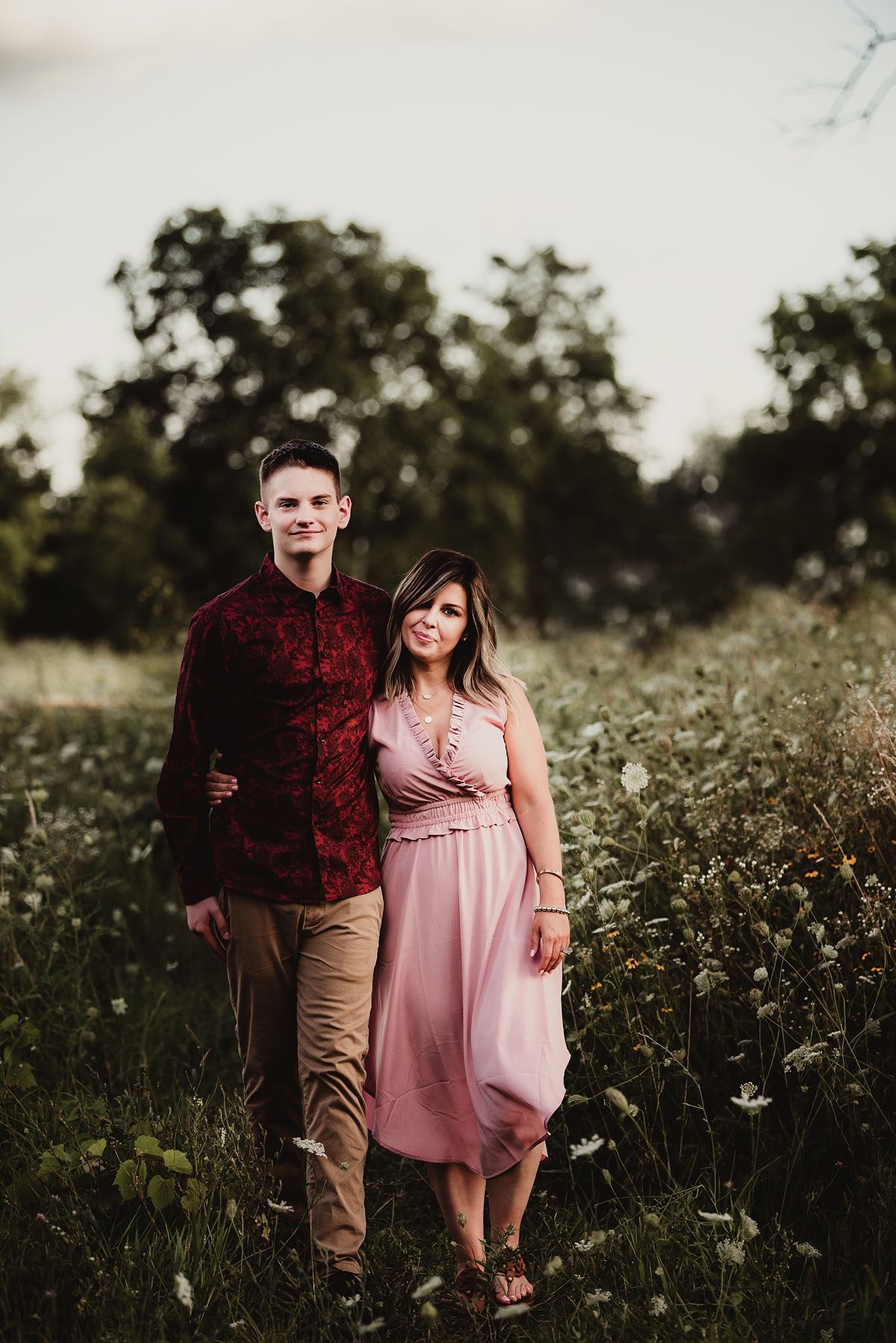 A couple standing together in a wildflower meadow during sunset.