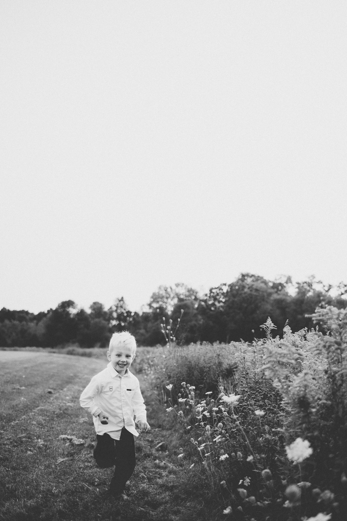 Child running through a meadow of wildflowers in black and white photography.