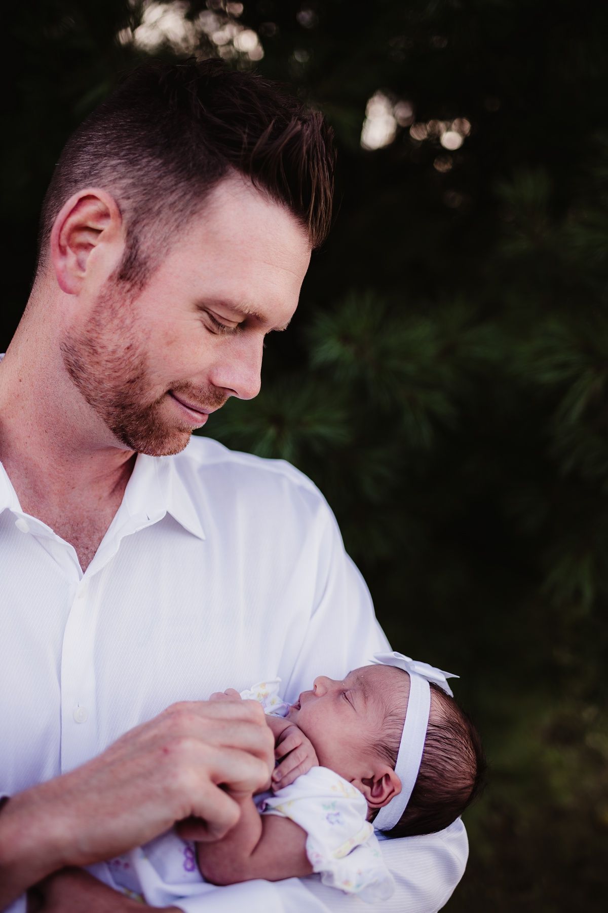 Intimate portrait of someone in white shirt gazing lovingly at a newborn baby.