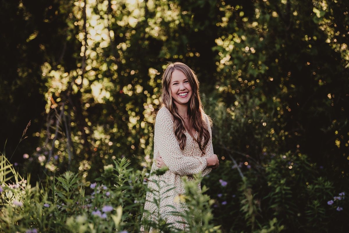 Natural light portrait in garden setting with cream colored dress among wildflowers.