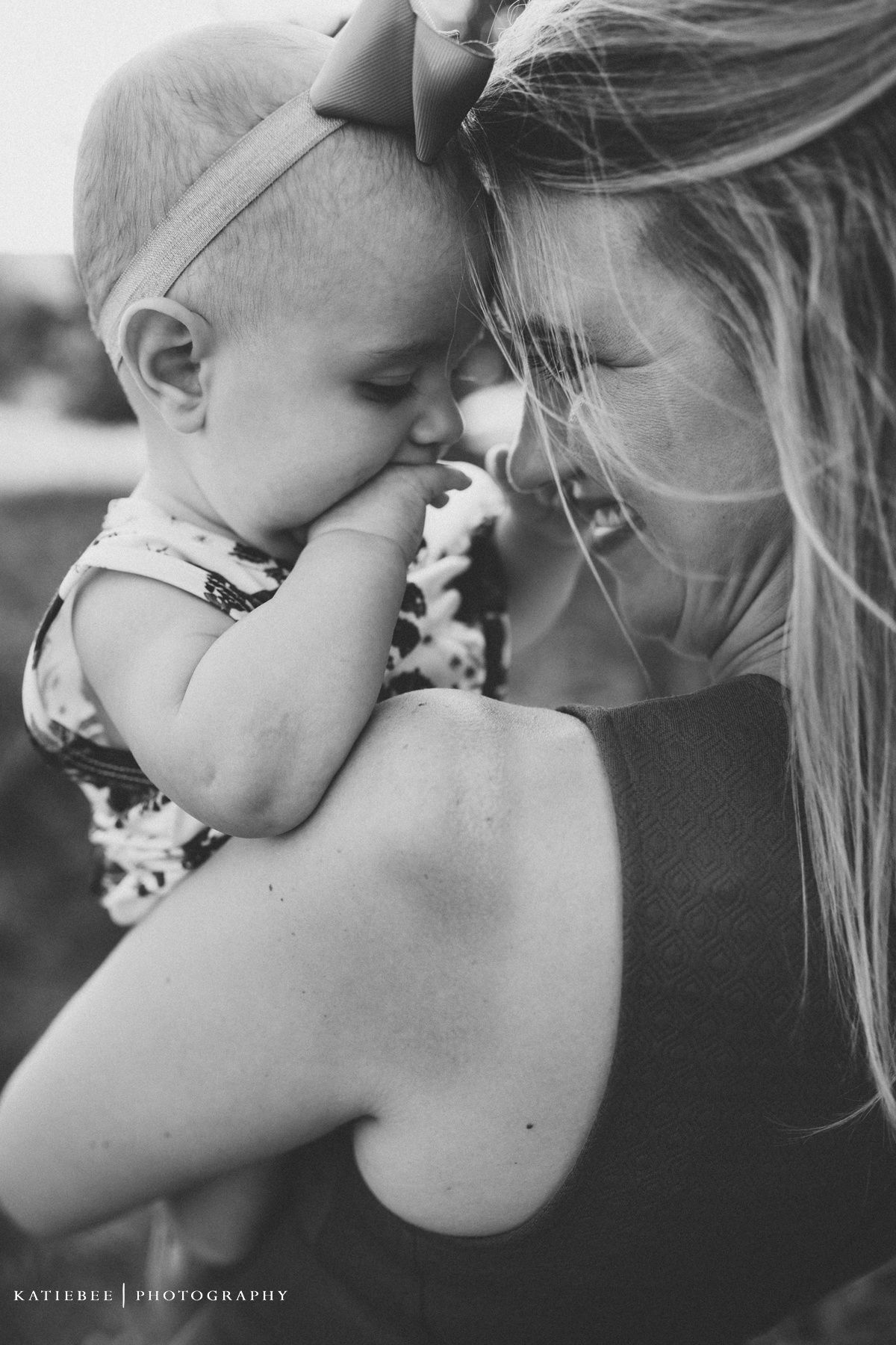 Intimate black and white portrait showing tender moment between mother and baby.