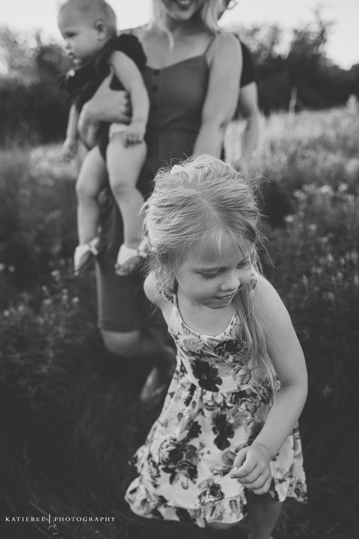 Black and white candid photo of children playing outdoors in a summer field.