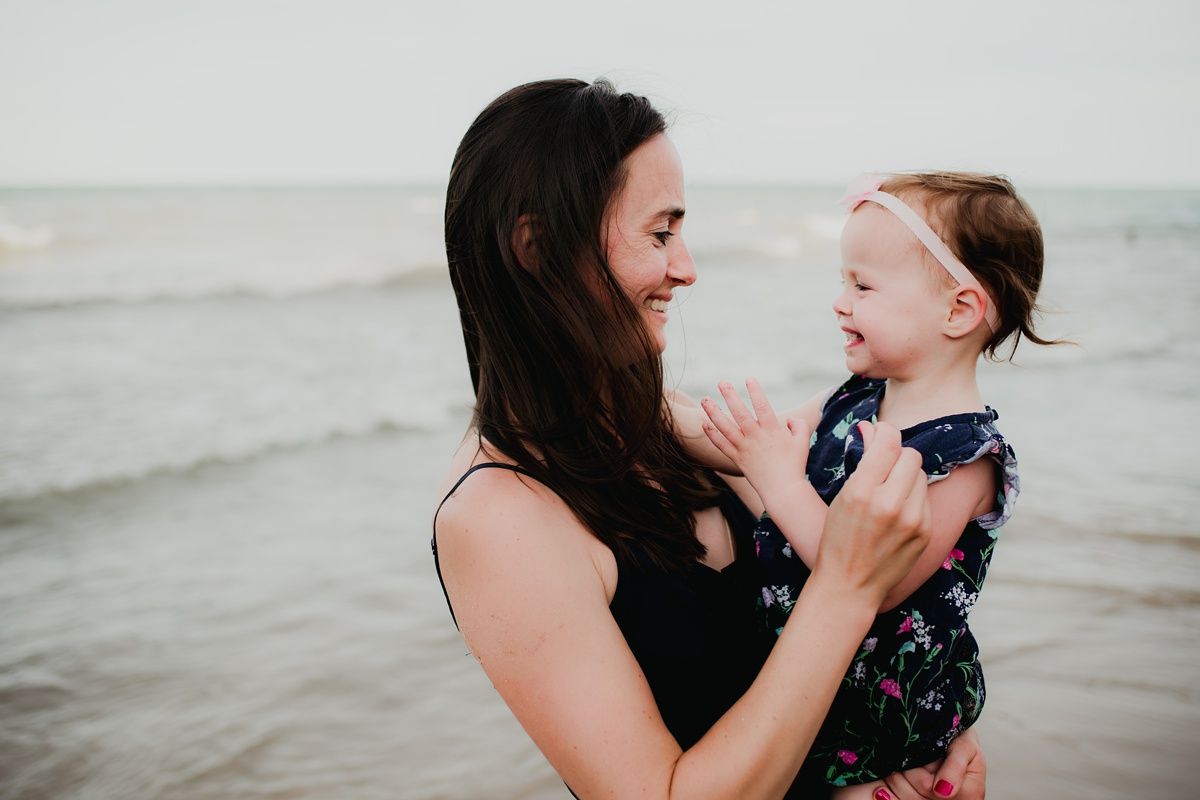 A joyful beachside moment between parent and child with waves in the background.