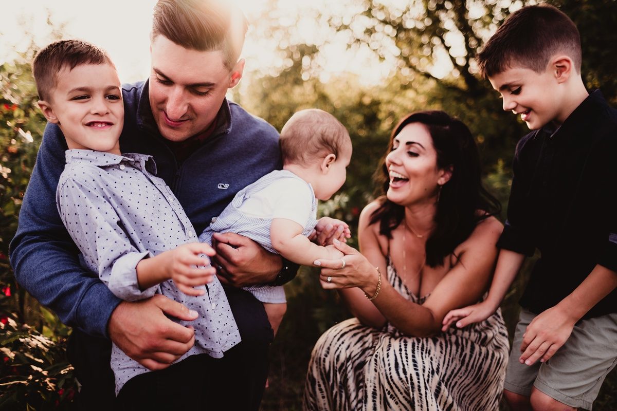 Candid family moment with parents and children laughing together outdoors.