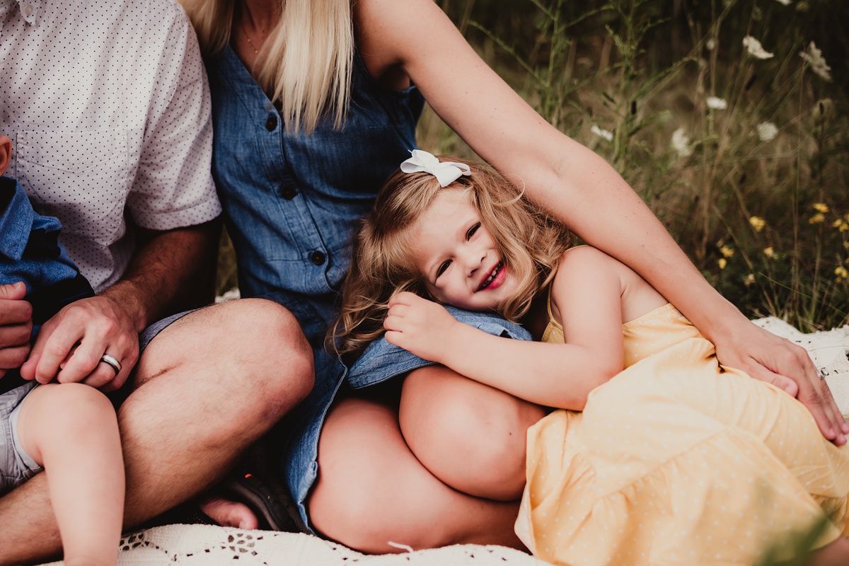 Candid family moment captured on a blanket outdoors with natural laughter.