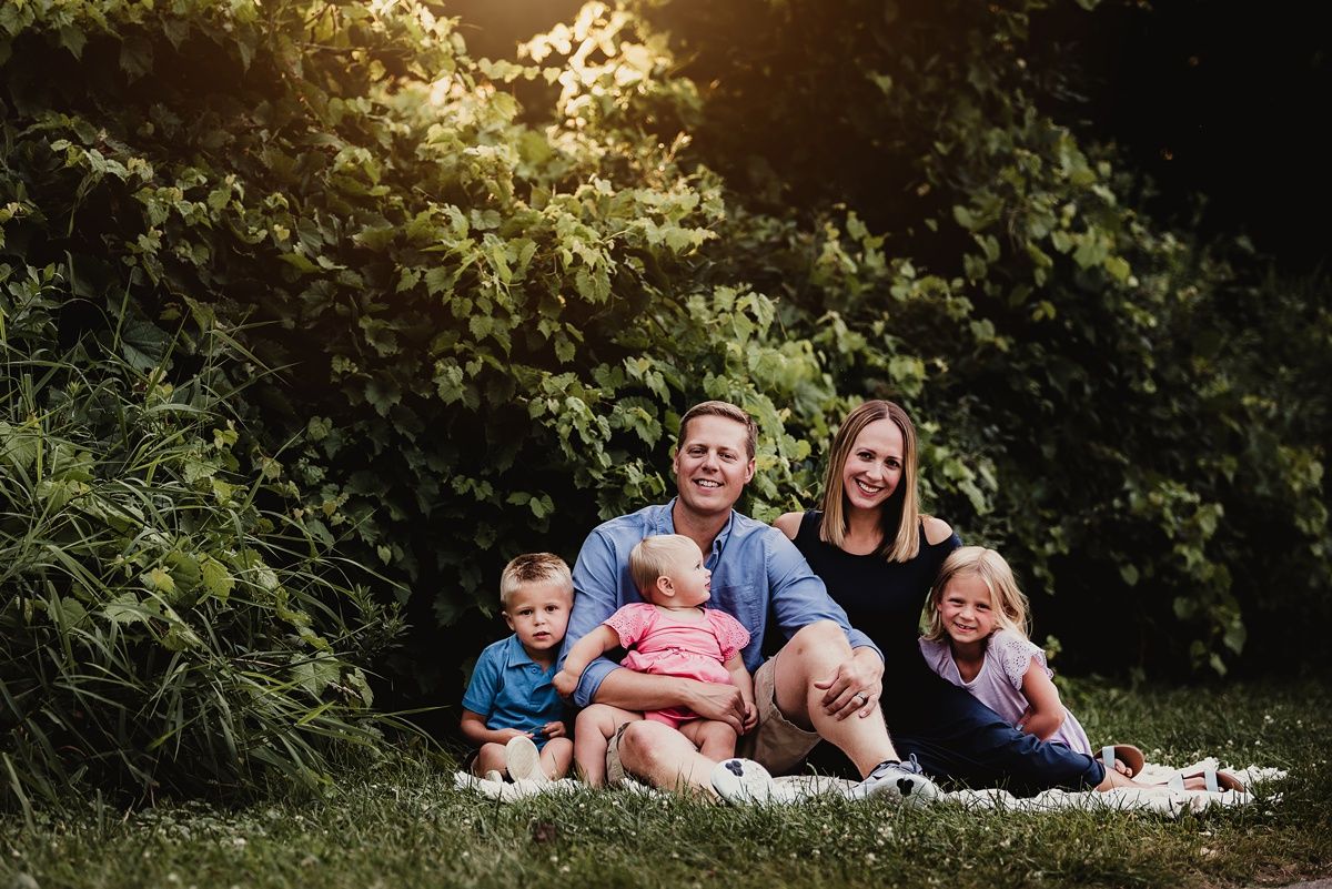 Family sitting together on grass during golden hour outdoor photo session.
