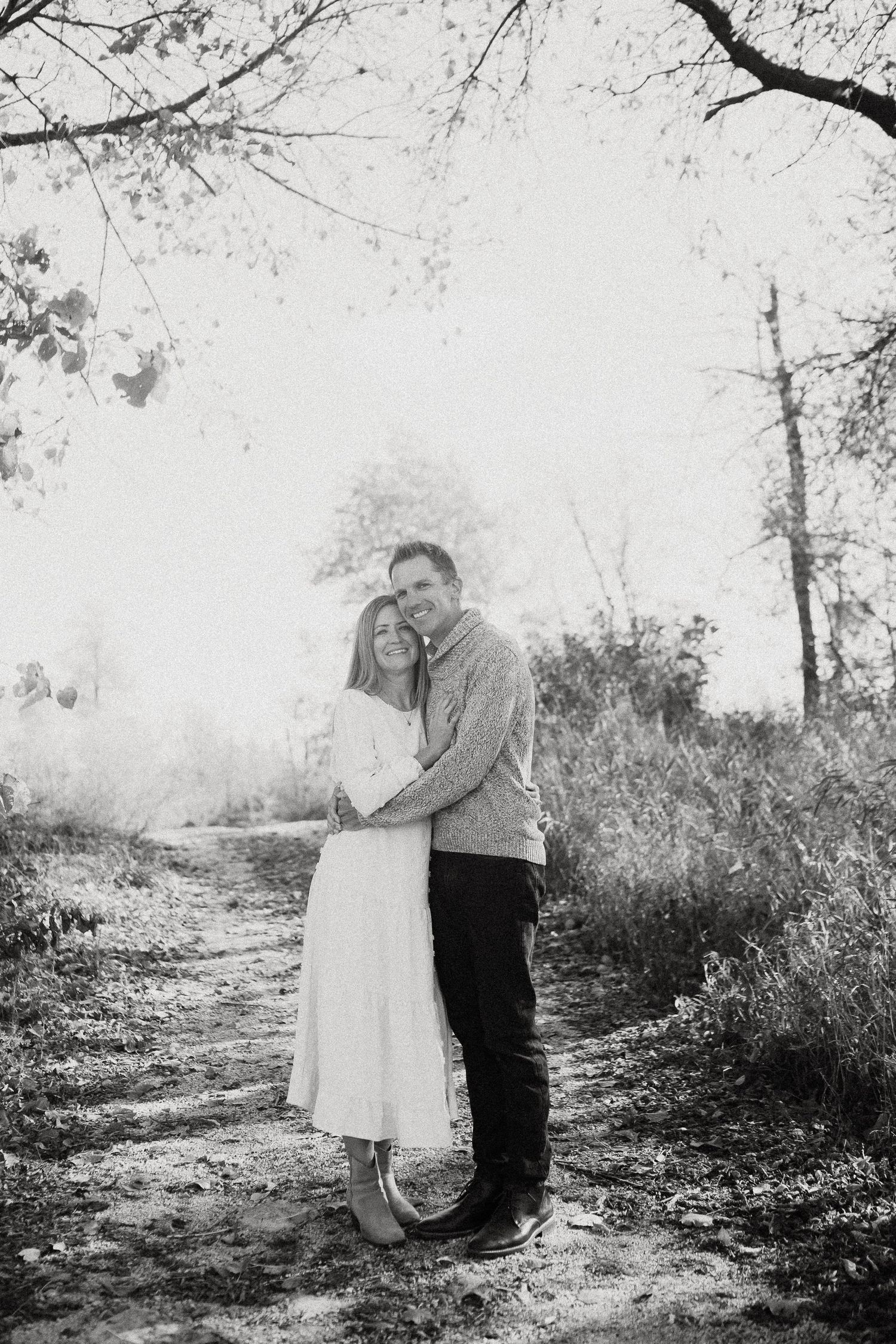 A romantic black and white photo sequence showing a couple embracing on a wooded hillside path.
