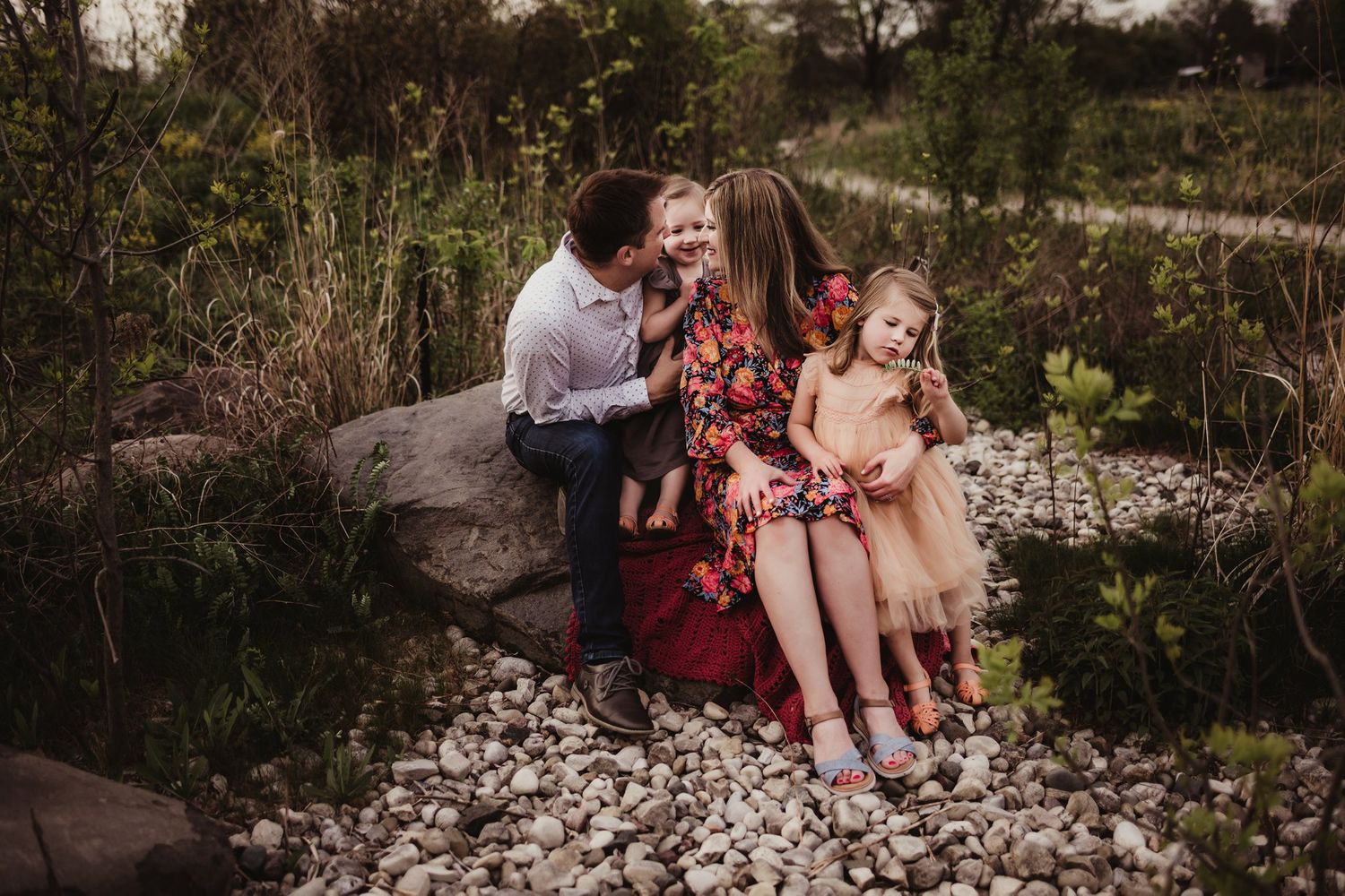 Joyful outdoor family moment captured on rocky terrain during golden hour.