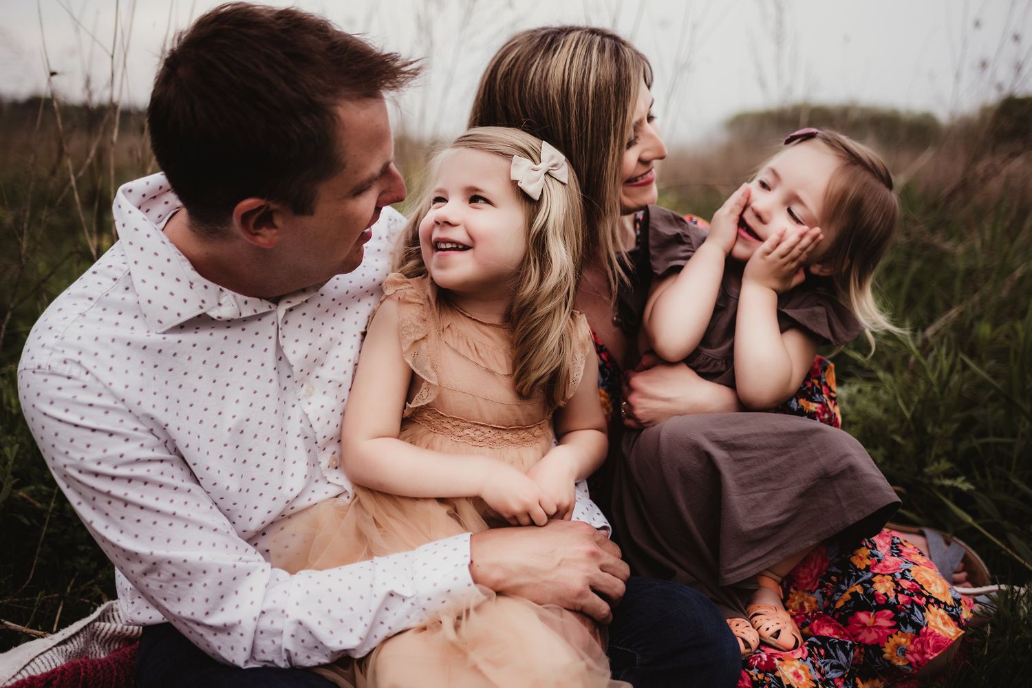 A joyful family sharing laughs and embraces during an outdoor photo session.