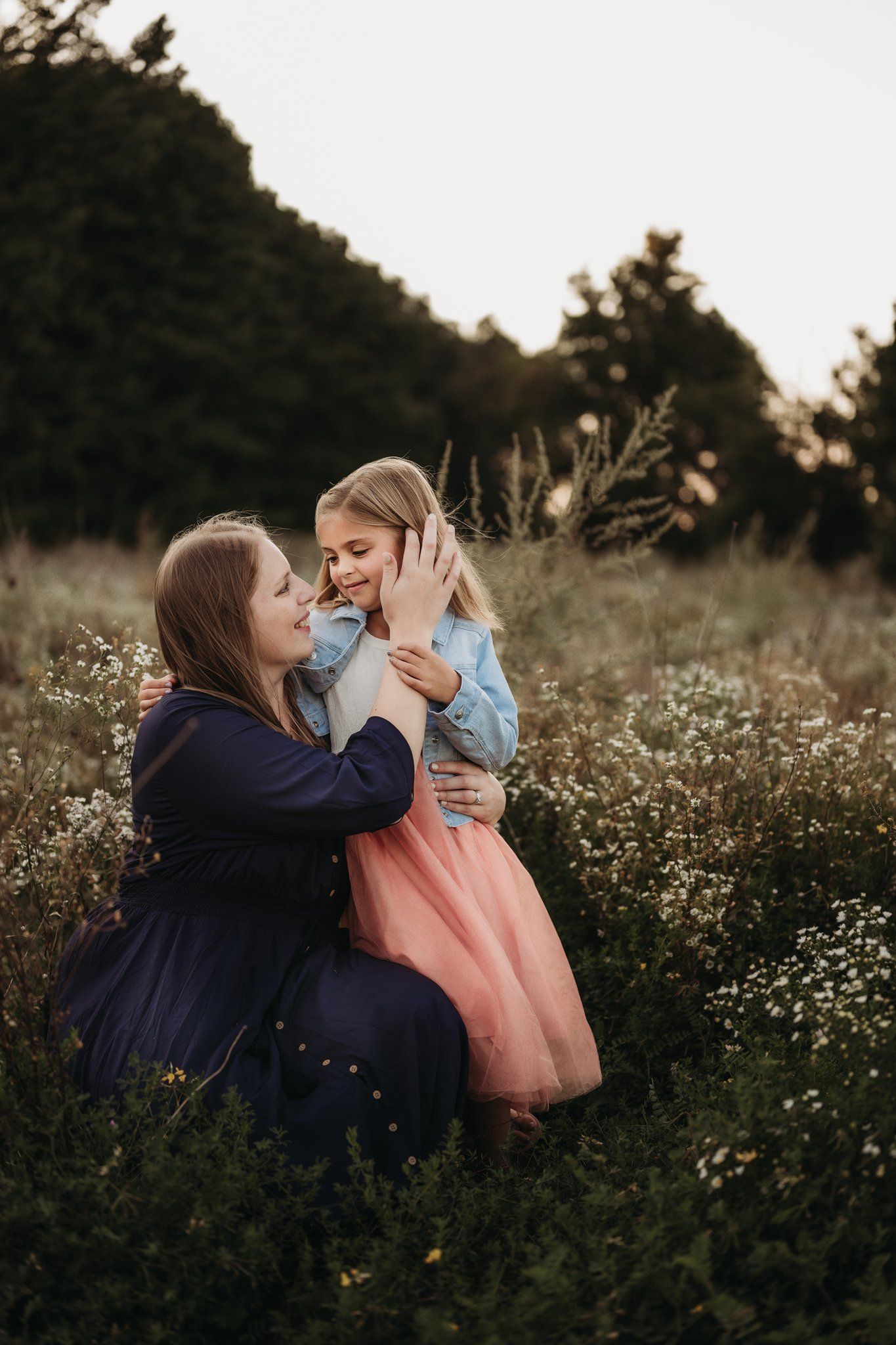 Mother and child sharing emotional moment together in blooming wildflower field.