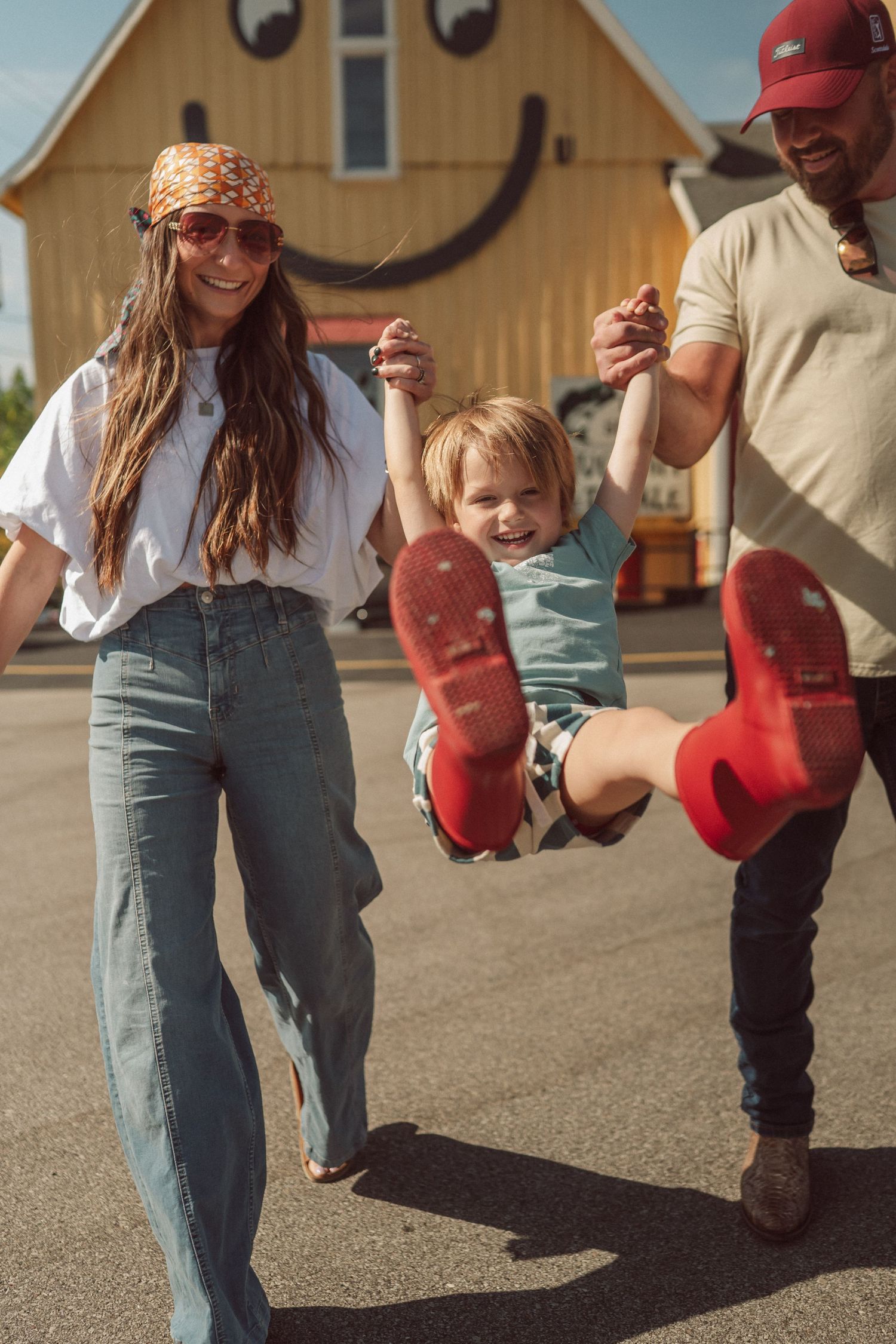 Playful sequence of red boots kicking and jumping on pavement near wooden buildings.