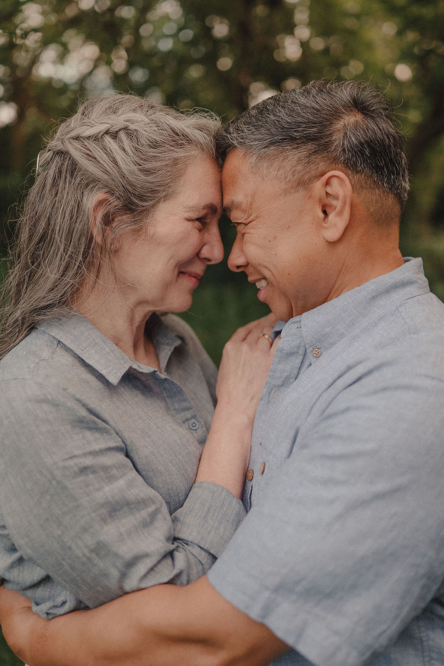 Loving interracial couple touching foreheads and smiling in a tender outdoor moment.