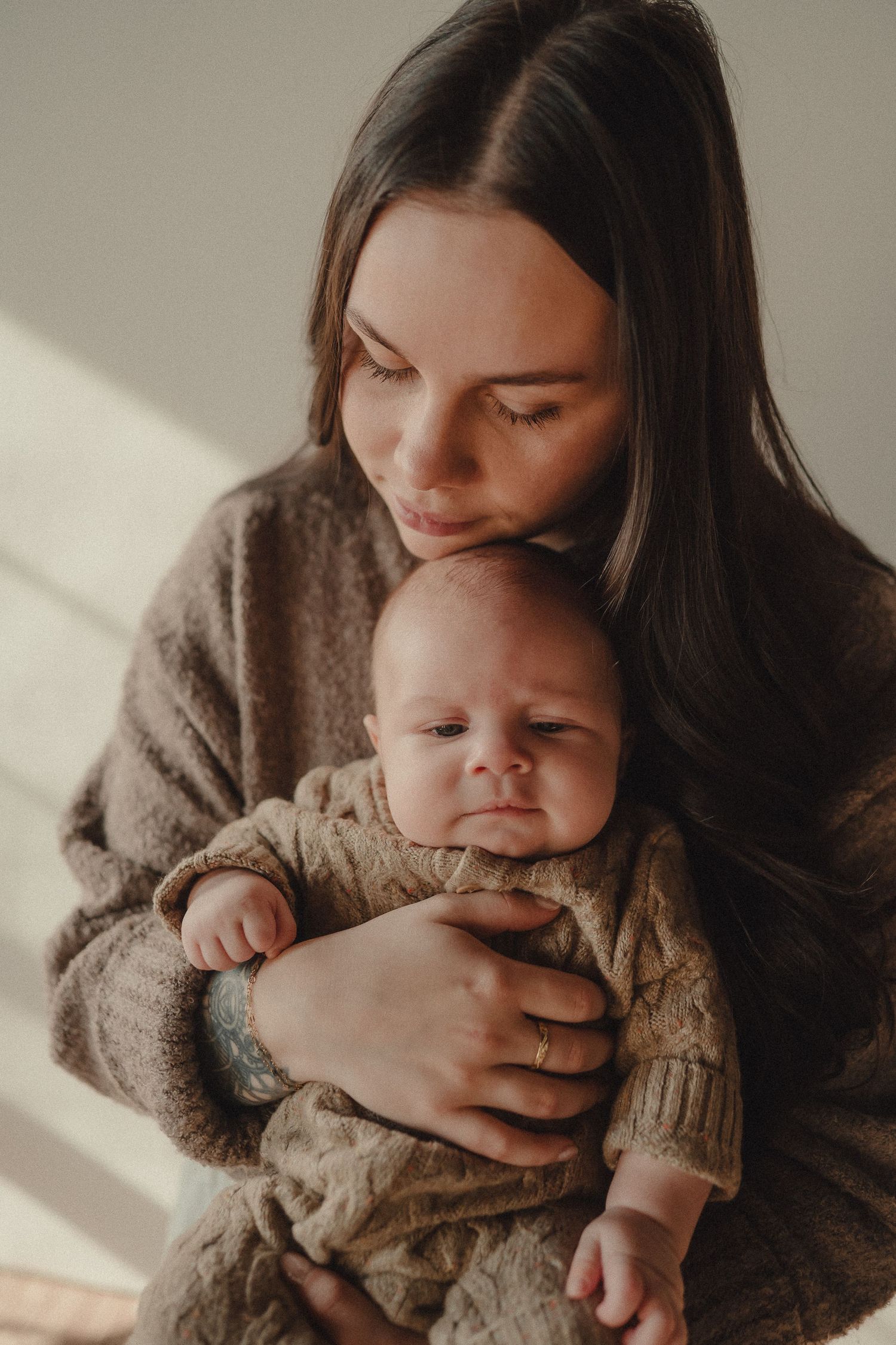 Close-up shots of a baby being lovingly held and cuddled in a cozy brown sweater.