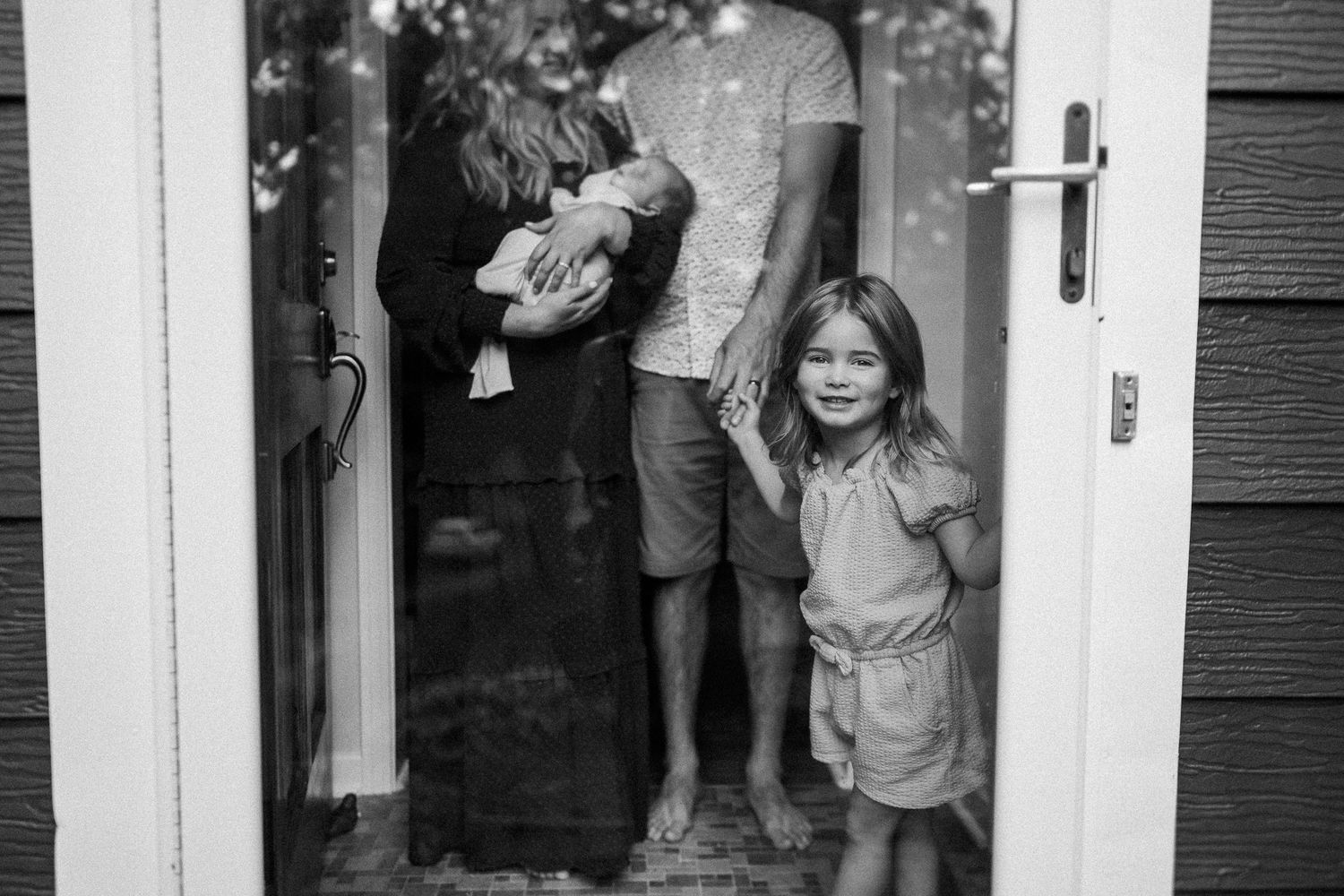 A candid black and white photo of people standing in a doorway of a house.