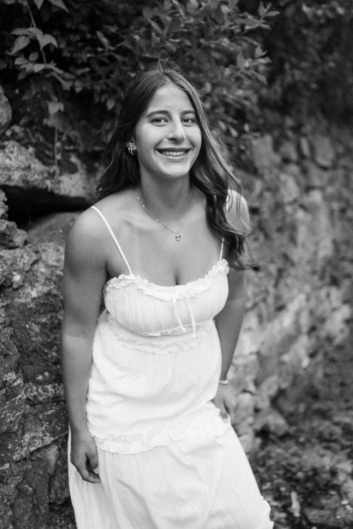 Black and white portrait against textured stone wall in natural lighting.