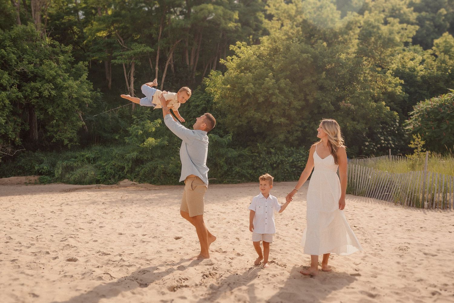 Family enjoying a playful moment together on a sandy beach at sunset.
