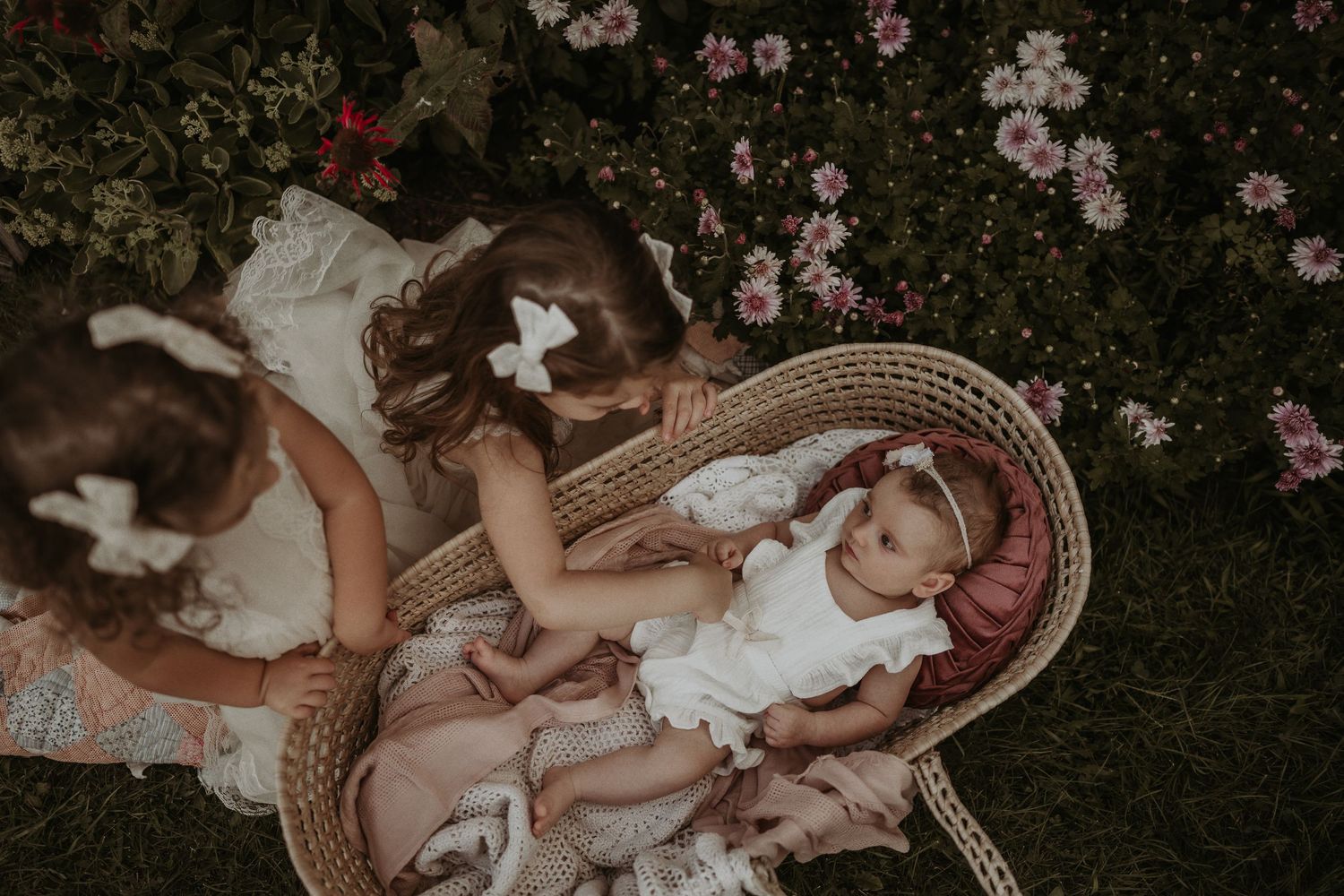 Moody garden portrait with woven basket and pink florals in background.