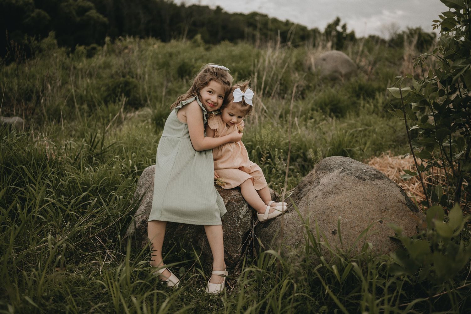 A touching family portrait captured on a rock amid wild grass and natural scenery.