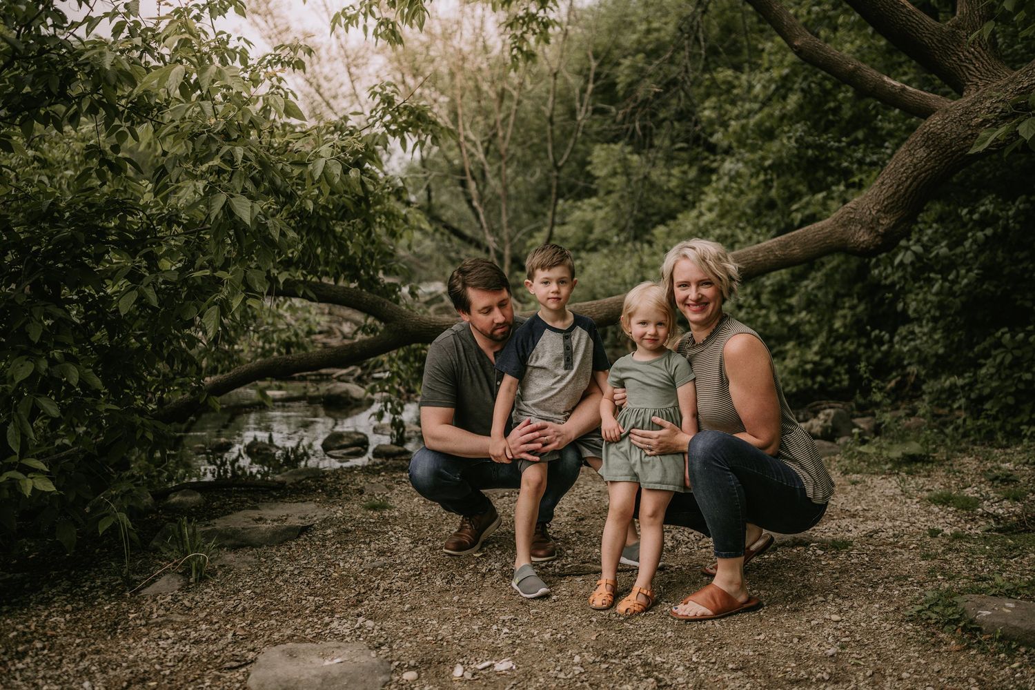 Family gathering outdoors together in a natural setting among trees and rocks.