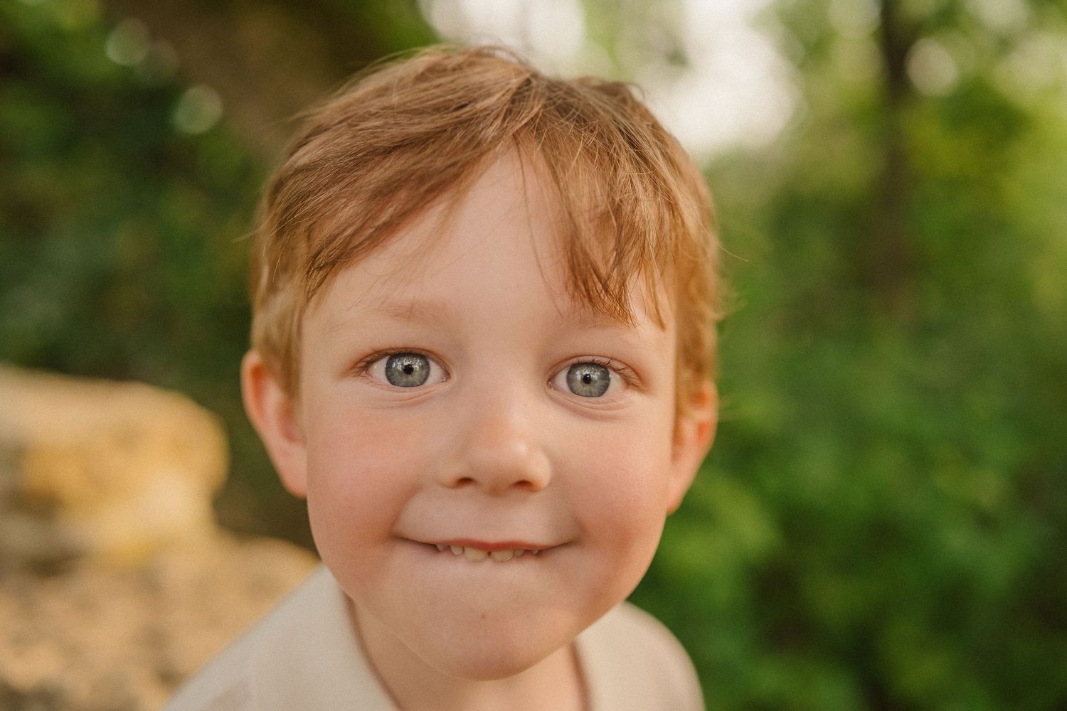 A close-up portrait showing bright eyes and a cheerful expression against a blurred natural background.