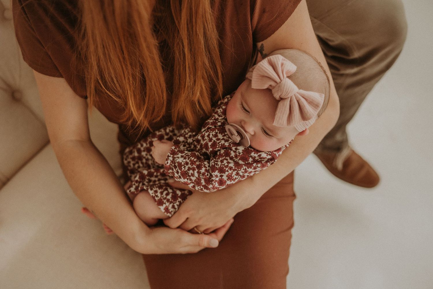 Close-up shot of a baby in a floral outfit with a matching bow headband.
