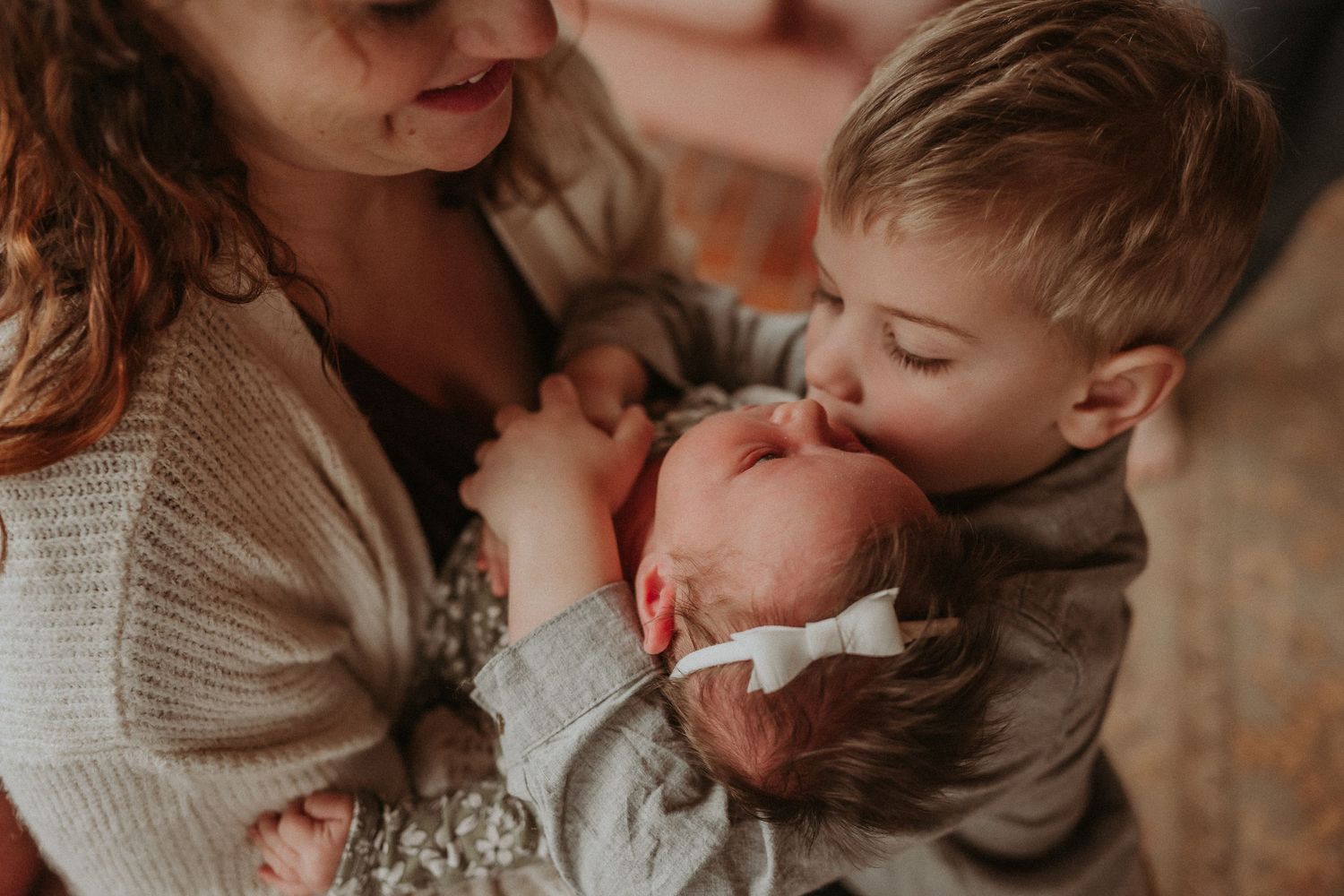 Intimate family moment captured in warm tones as siblings share first meeting.