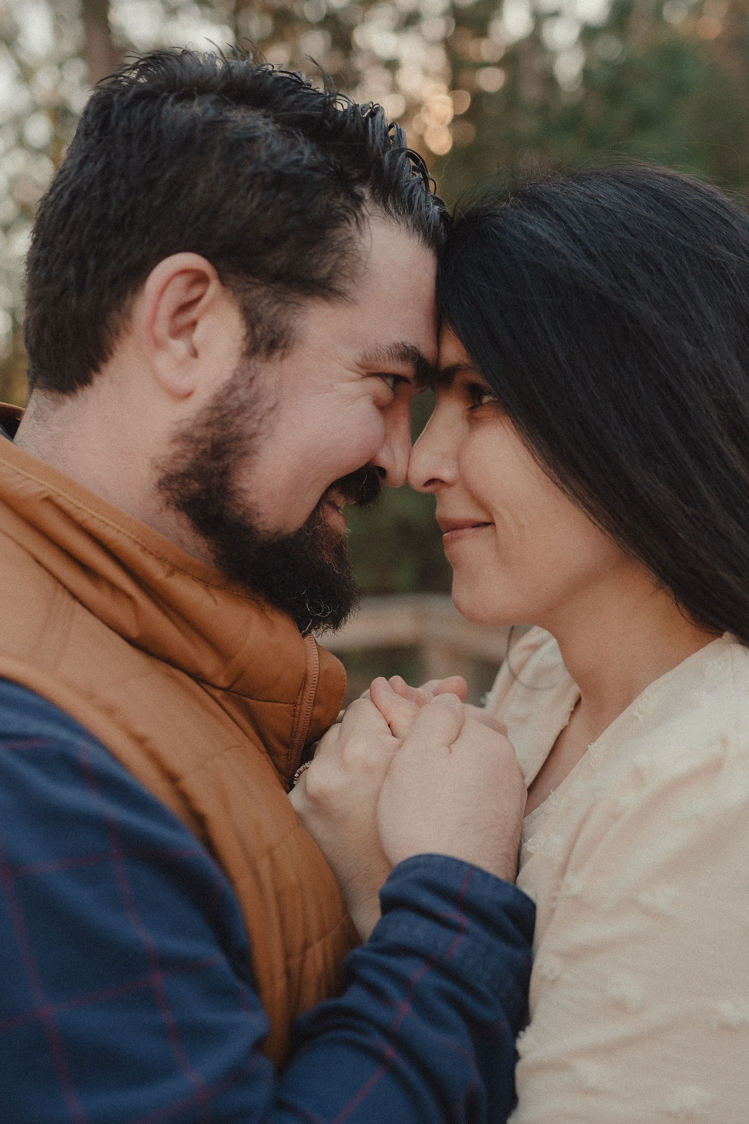 A tender moment shared between a couple in warm autumn clothing against a forest backdrop.