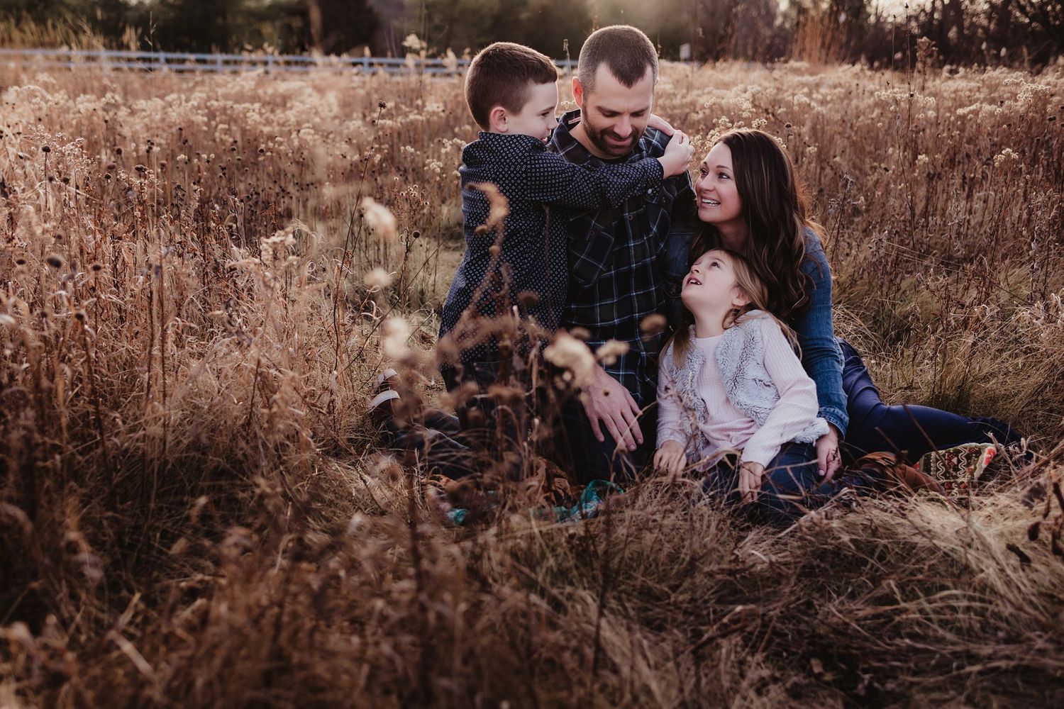 Family sitting together in field during golden hour photography session.