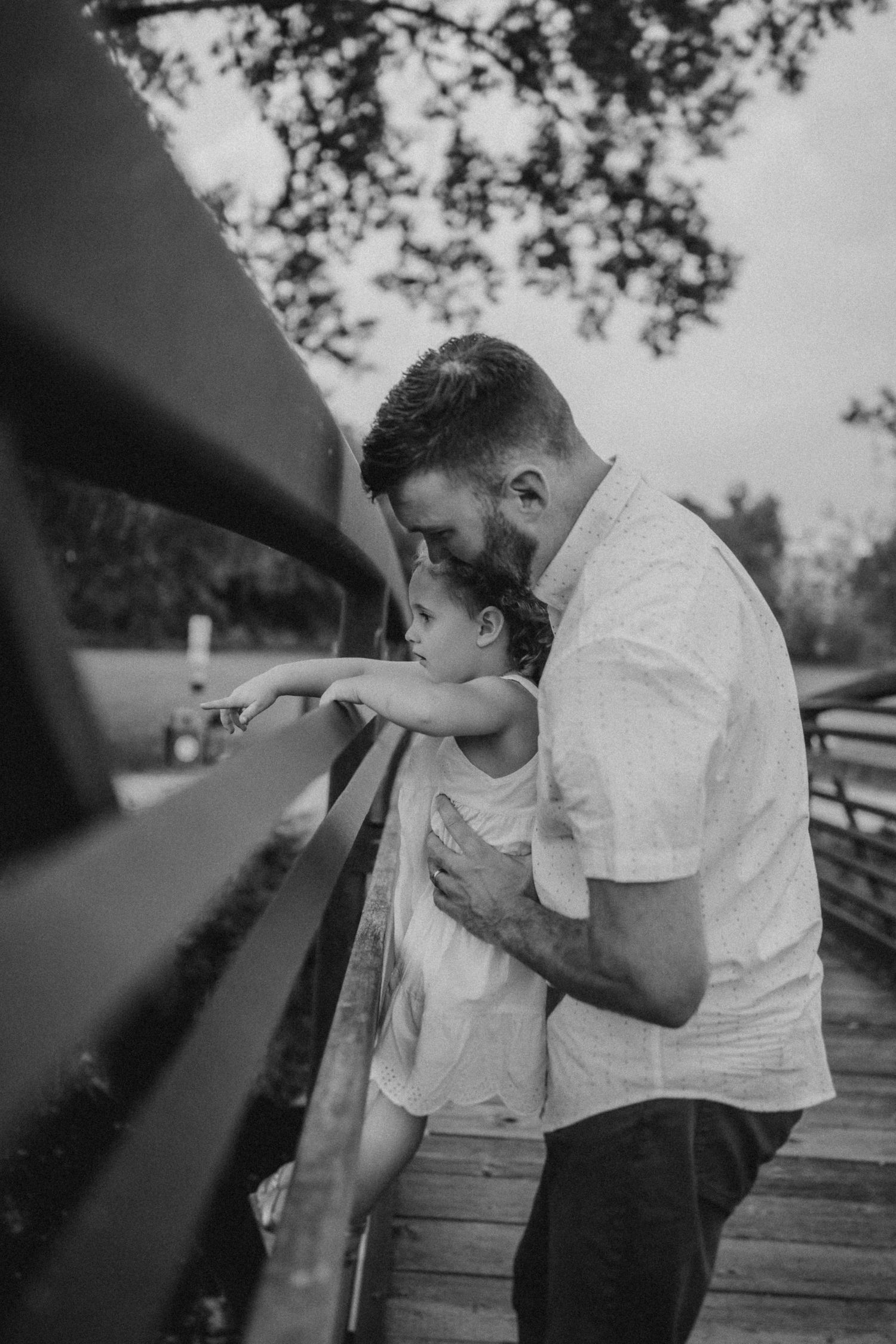 A touching moment shared on a wooden bridge while looking at the water below.