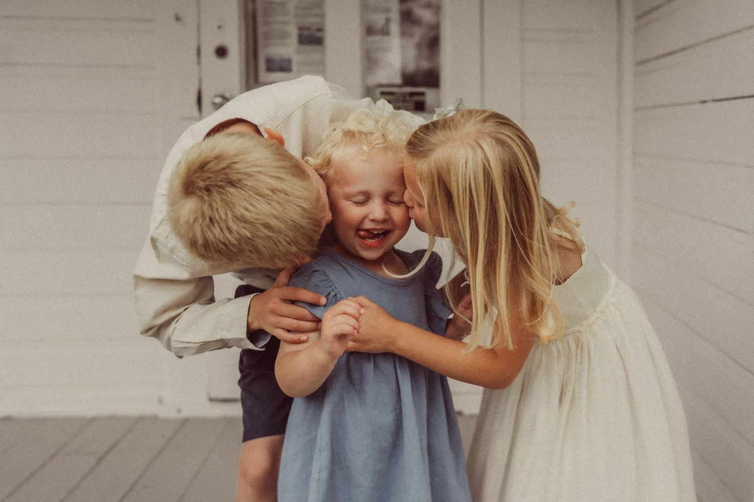 Candid moment of laughter and hugs shared on a white farmhouse porch.
