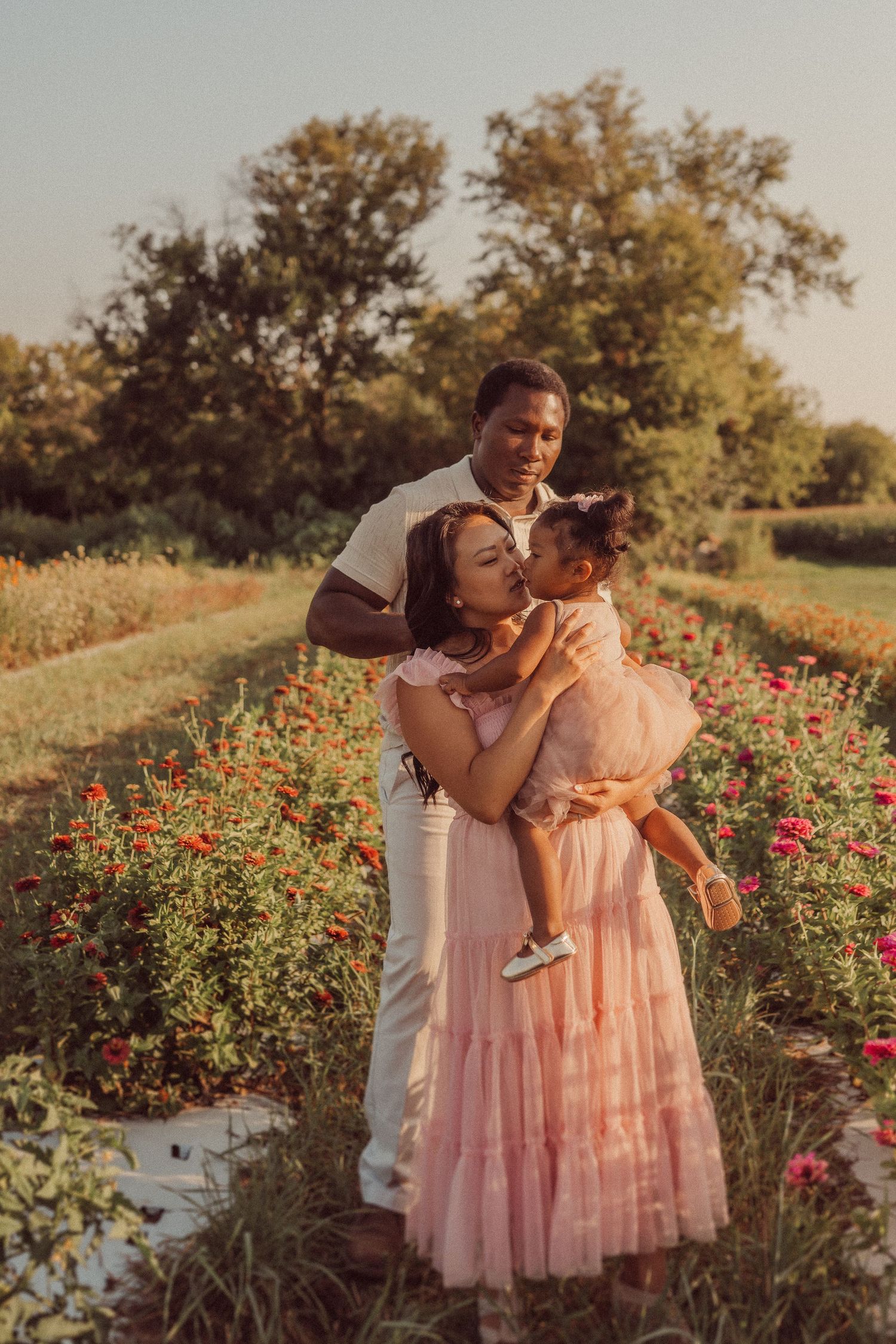A tender family moment captured among blooming flowers during golden hour.