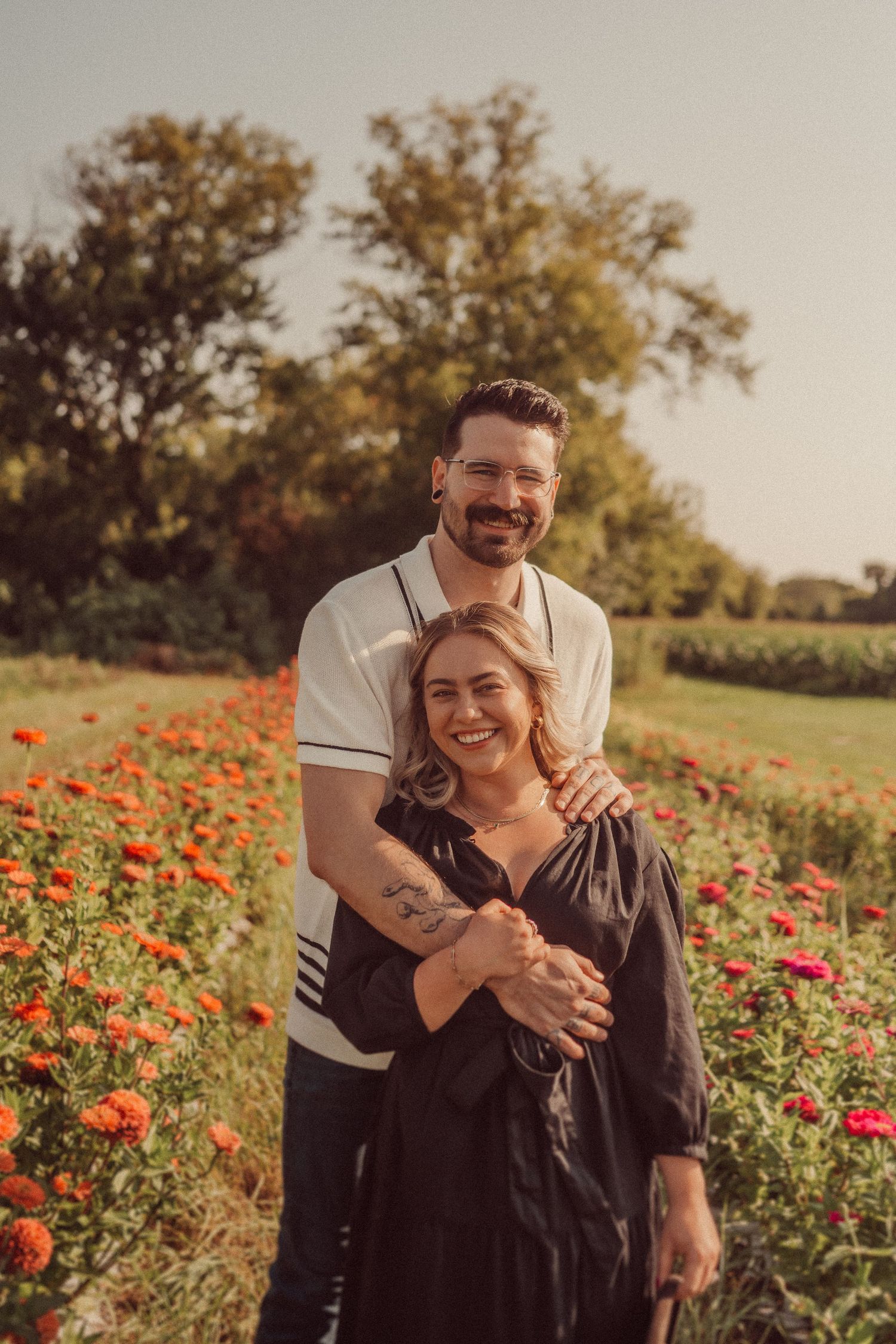 A romantic couple embraces in a field of vibrant red poppies during golden hour.