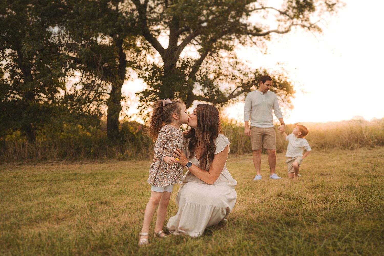 Family enjoying golden hour together in a scenic field with trees.
