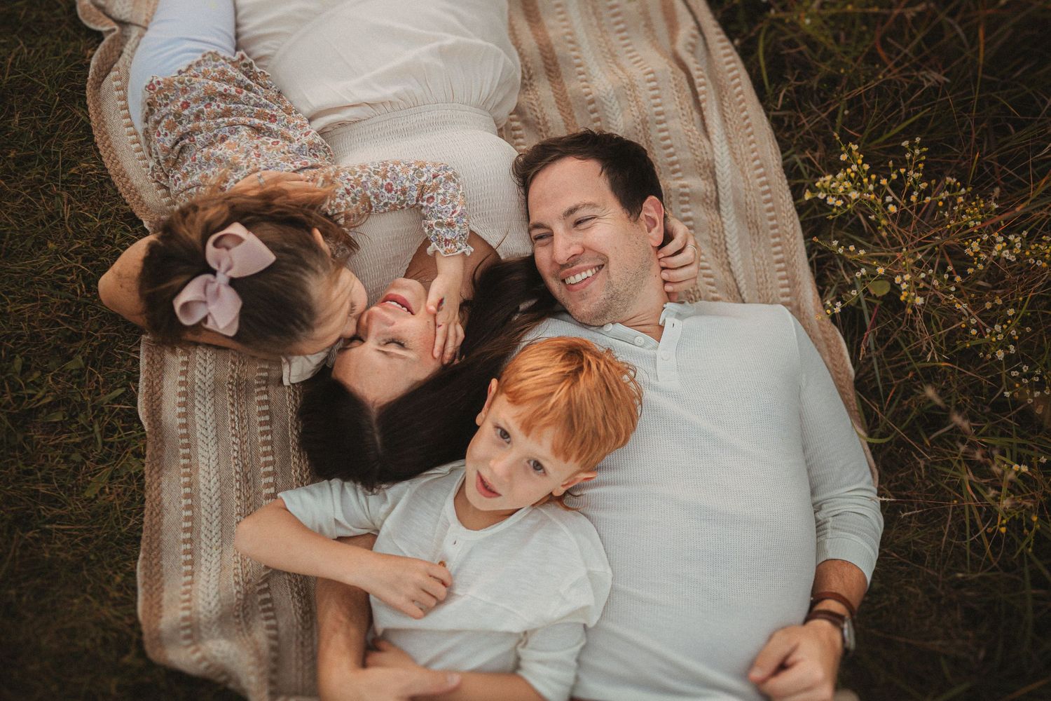 Overhead view of family lying on blanket outdoors with small dog.
