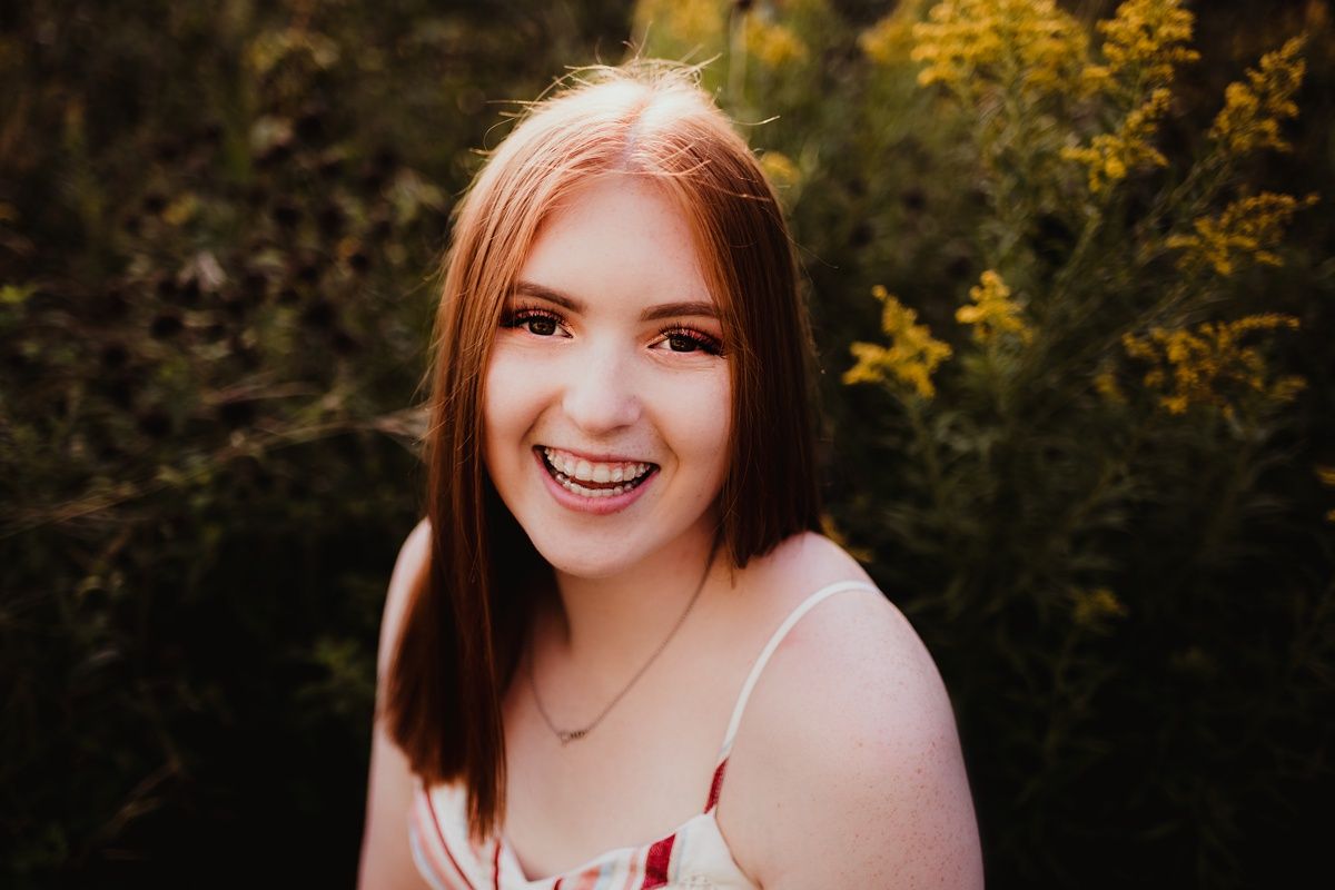 A close-up outdoor portrait with natural bokeh and yellow flowers in the background.