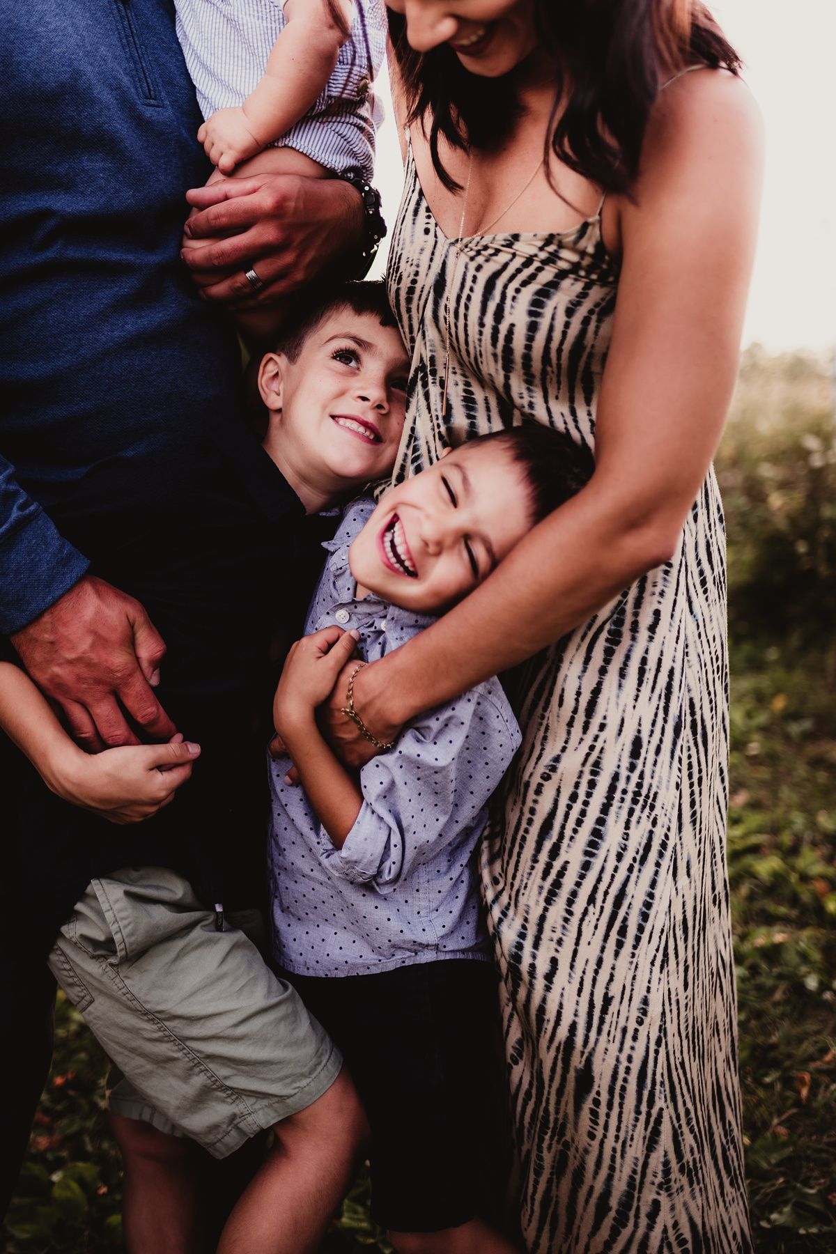 Candid moment of family embracing and laughing together outdoors.