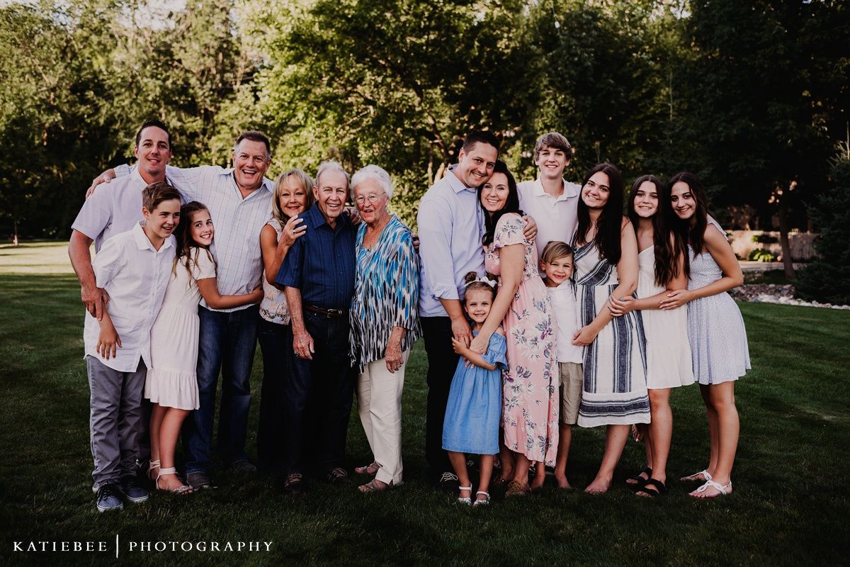 Multi-generational group photo with coordinated outfits standing together on a sunny lawn.