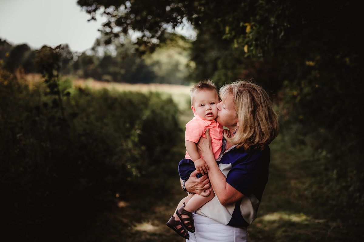 An intimate family moment captured outdoors with natural lighting and forest scenery.